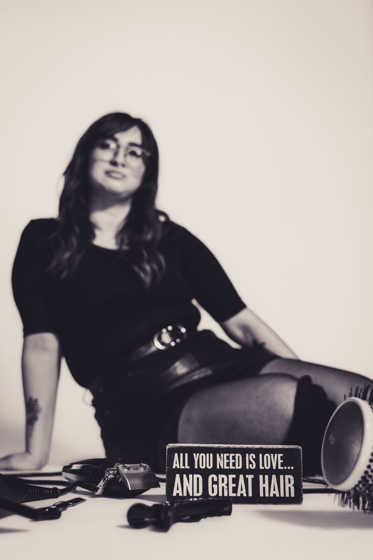 Monochrome photo with hairstyling tools and sign reading 'All you need is love and great hair'.