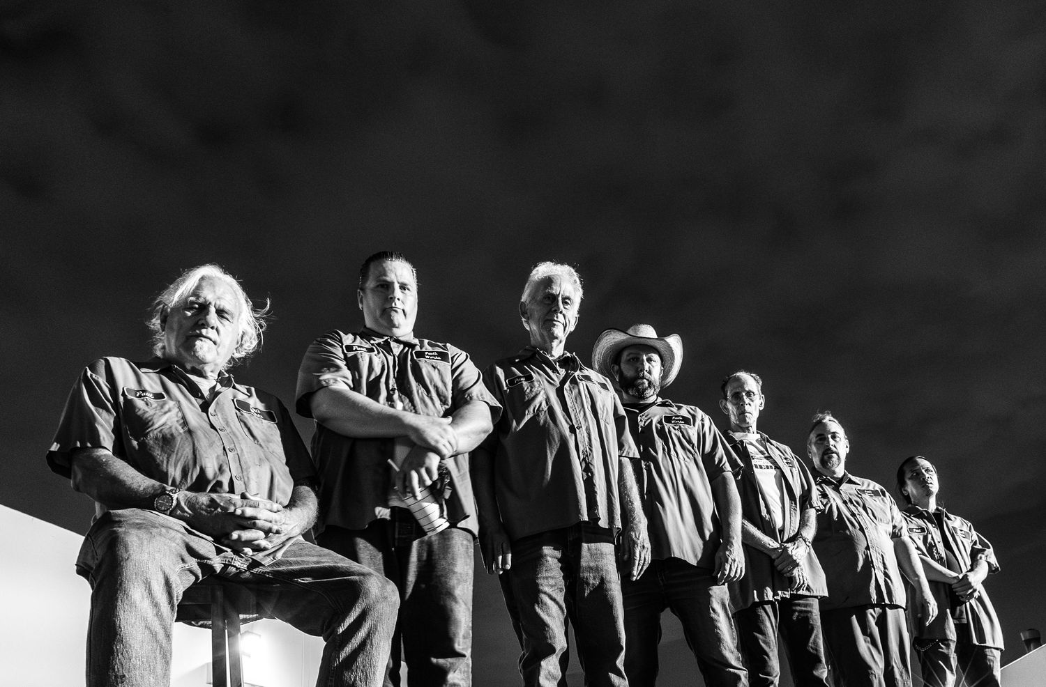 Dark silhouettes of people standing in line against contrasting background.