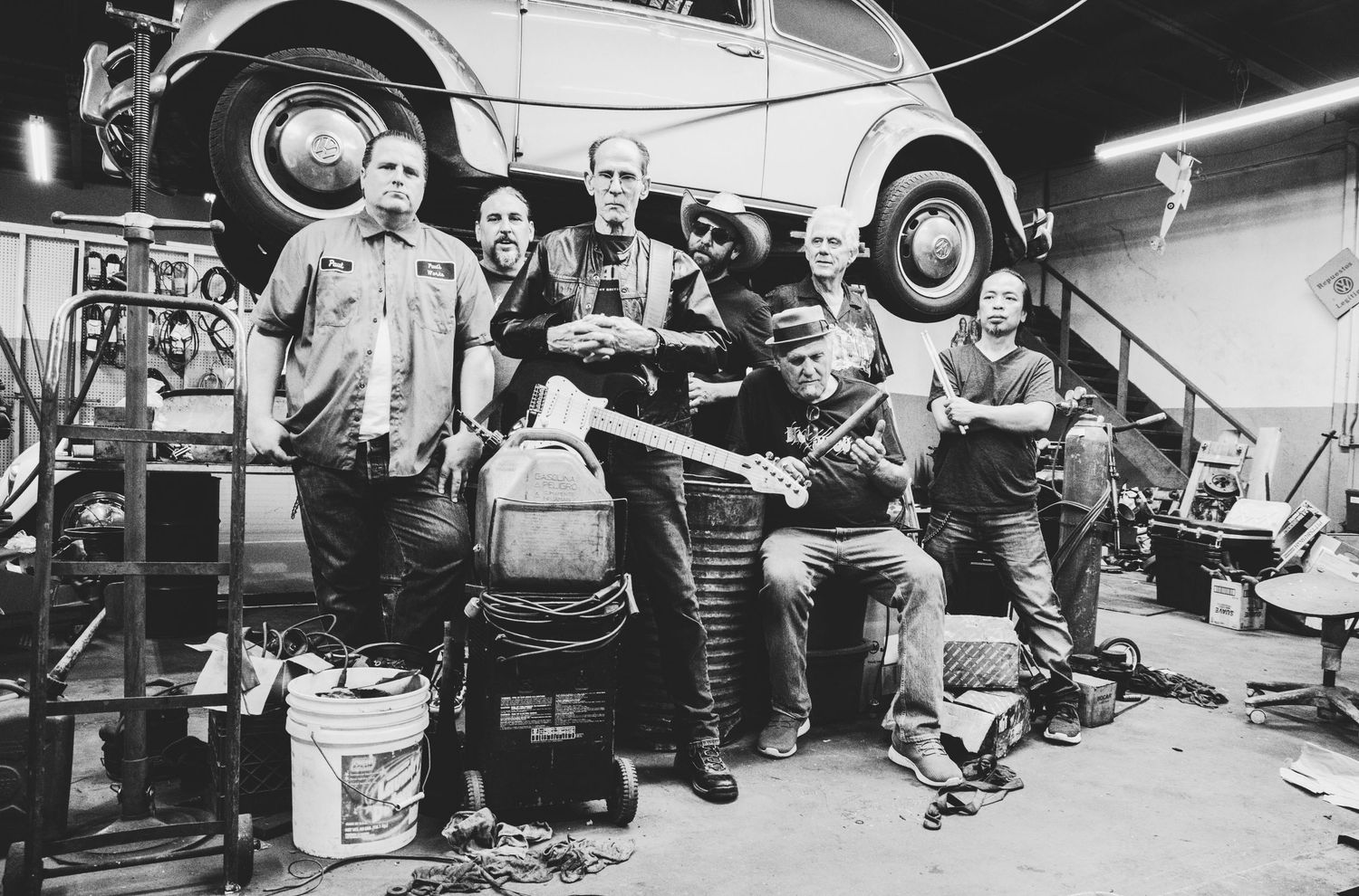 People relaxing near vehicles in outdoor mechanical or garage setting.