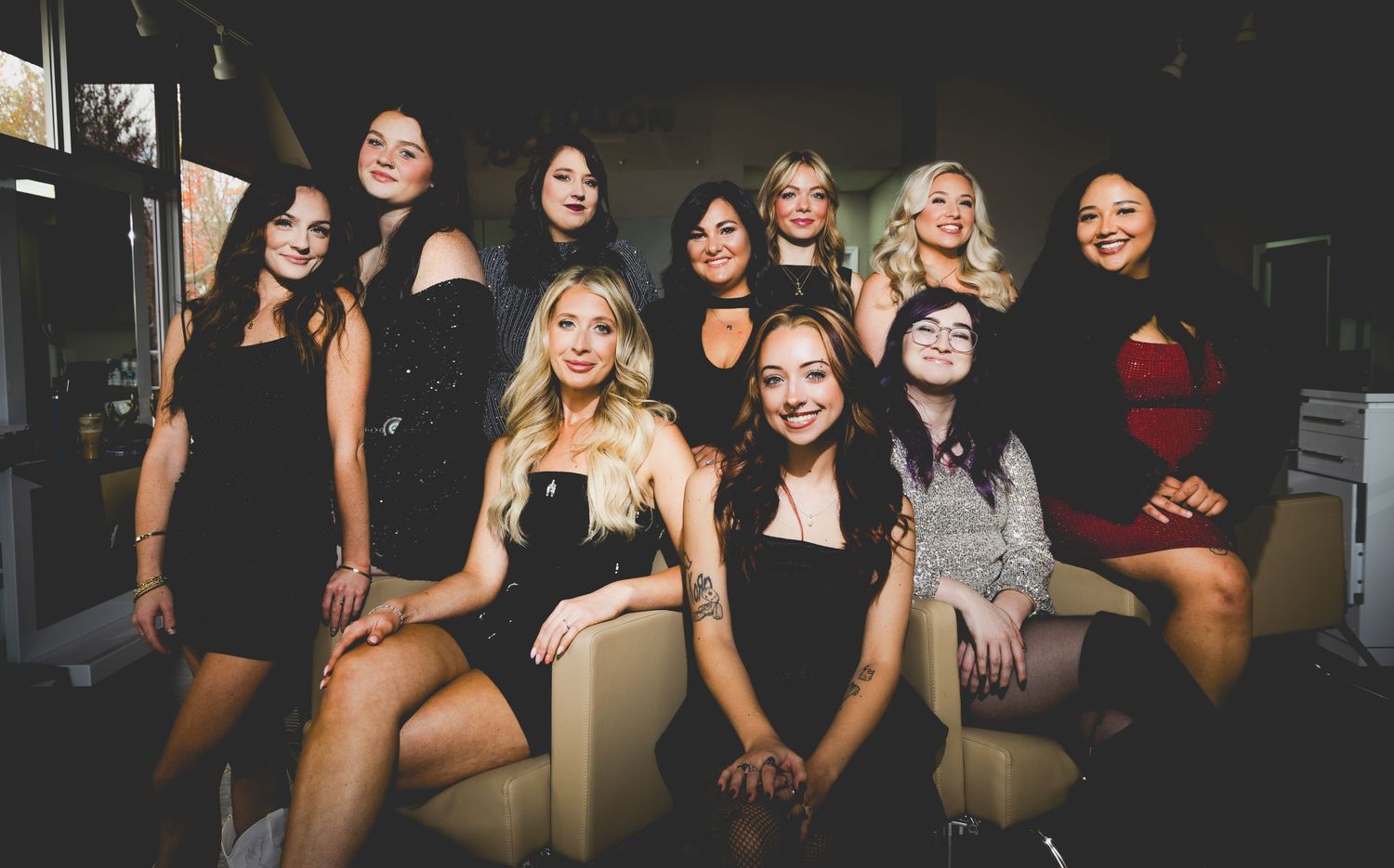 A casual group photo of friends in black outfits posing together on a couch.