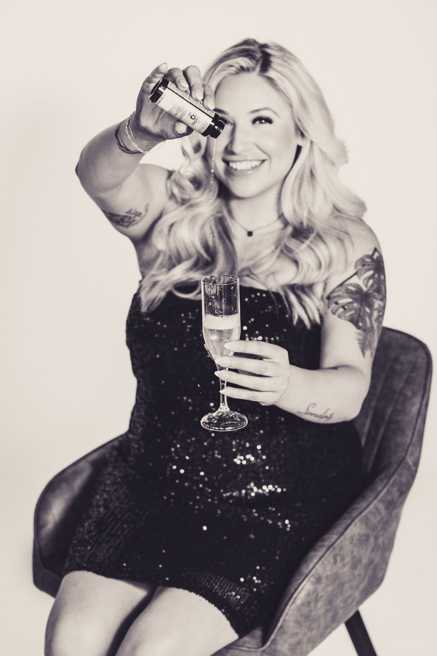 A glamorous party photo featuring a sparkly black dress and champagne glass in black and white.