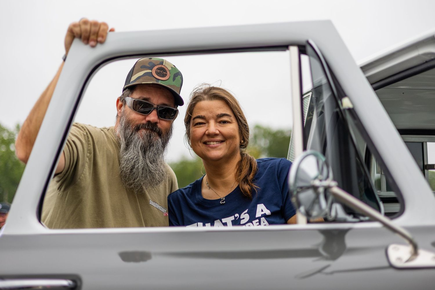 People enjoying a classic car show and posing with vintage vehicles.