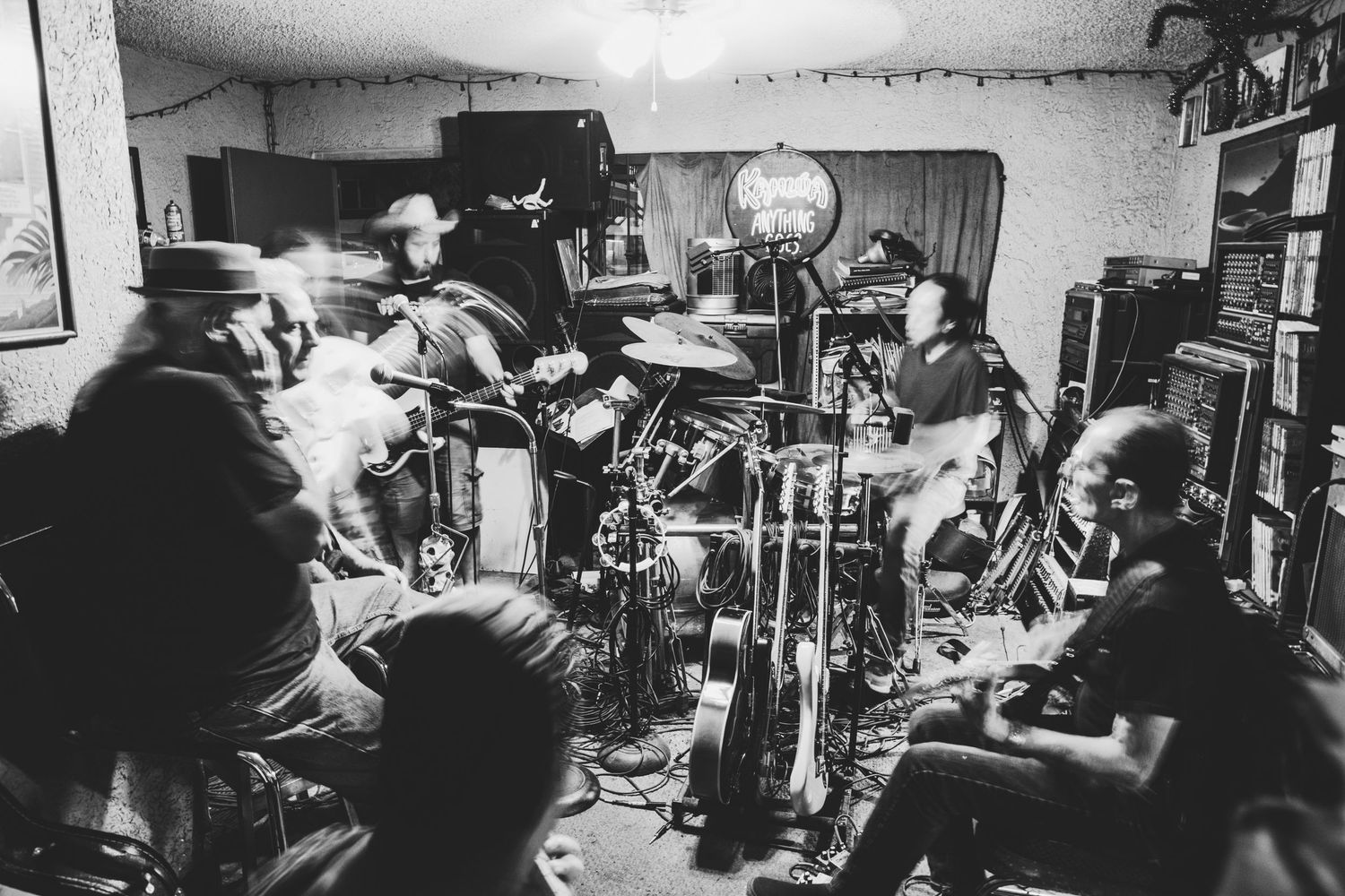 Musicians performing in a dimly lit indoor space with instruments and equipment.