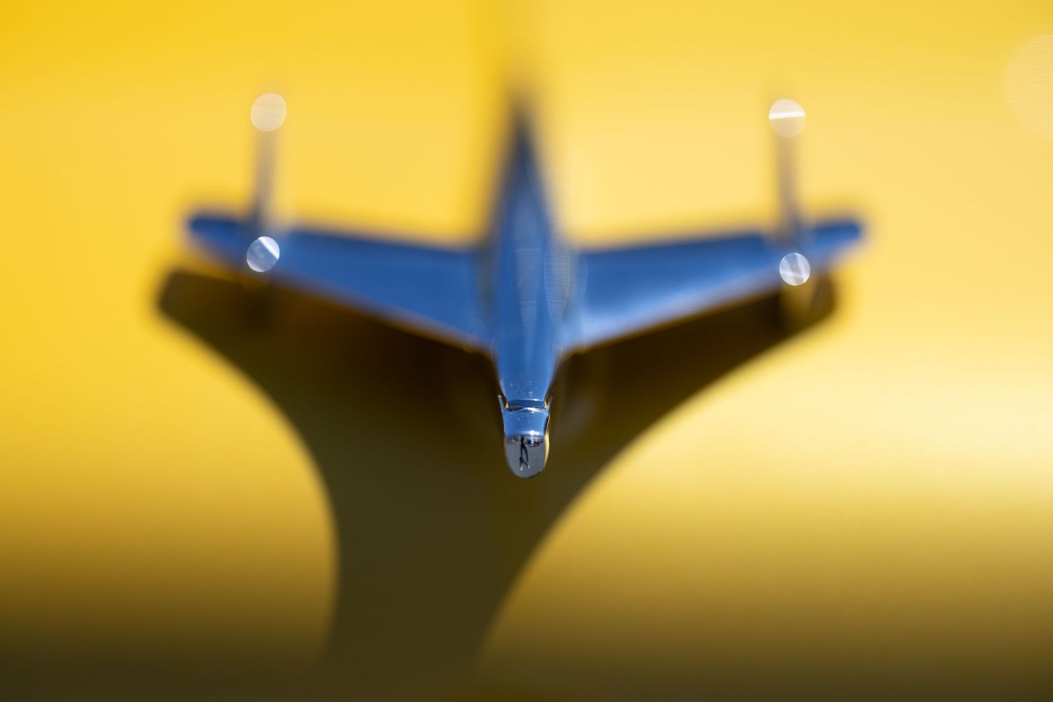 Closeup detail shots of a vintage car hood ornament against yellow background.