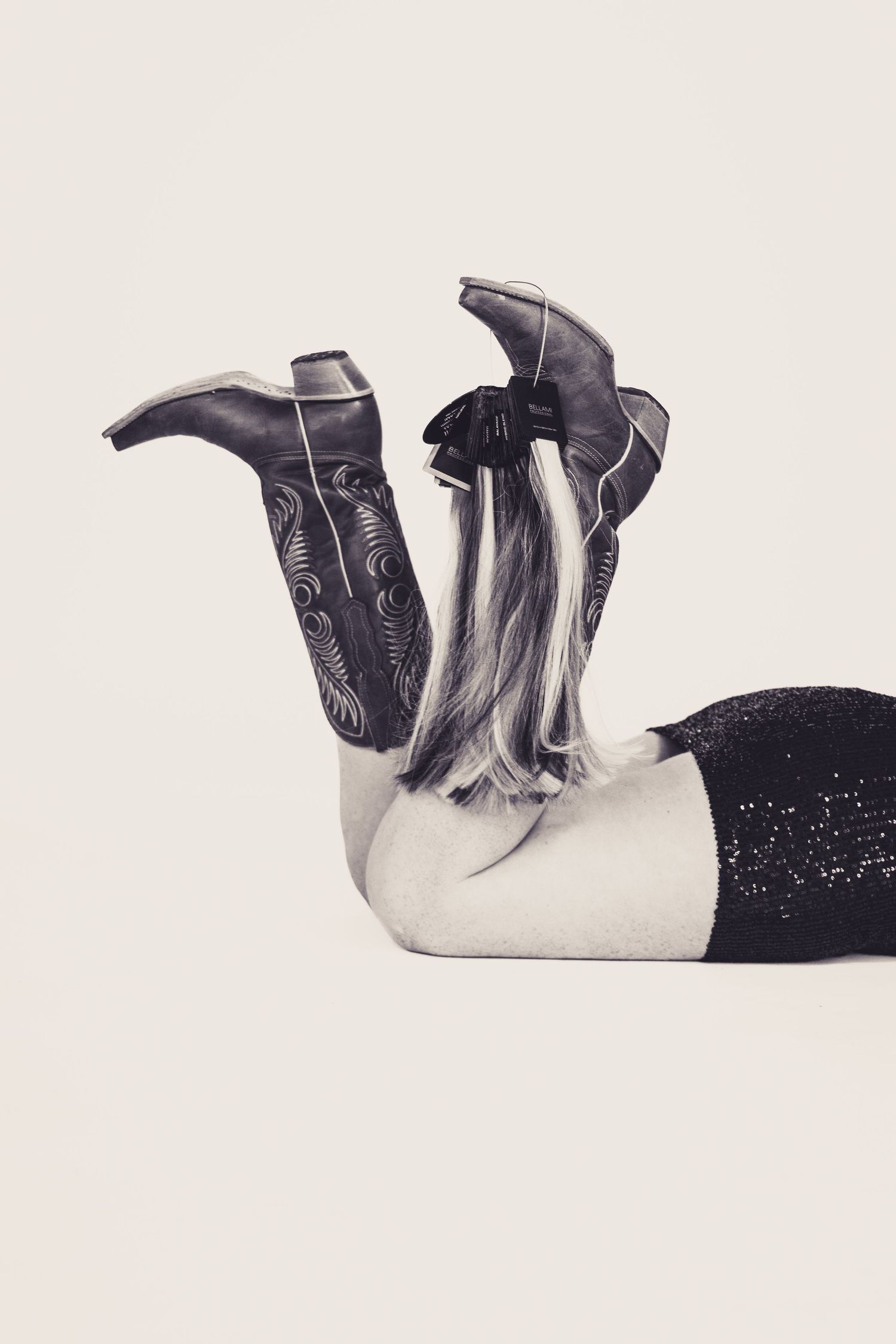 Artistic black and white photo showing cowboy boots against light background.