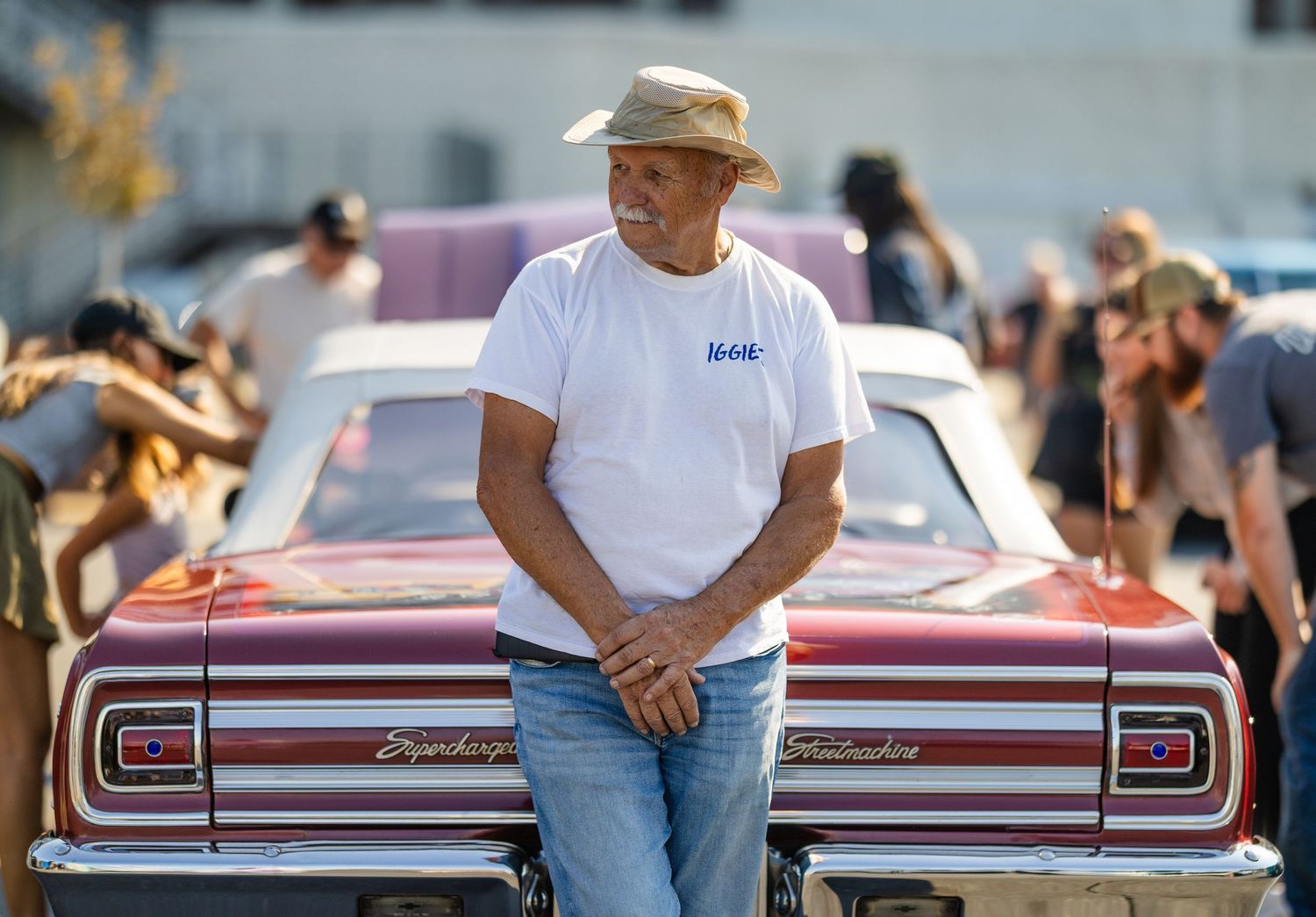 A row of classic cars lined up at an outdoor auto show with spectators viewing.