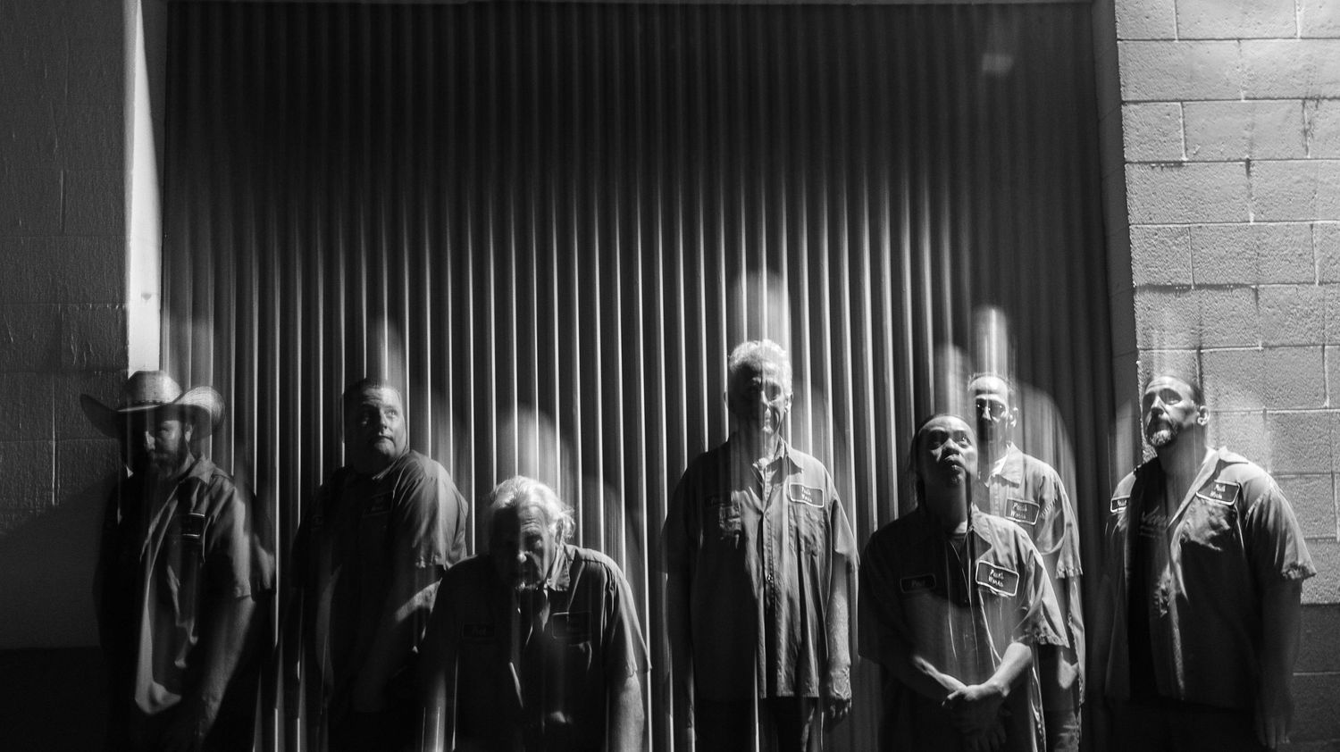 People positioned against industrial wall with vertical lines creating geometric pattern.