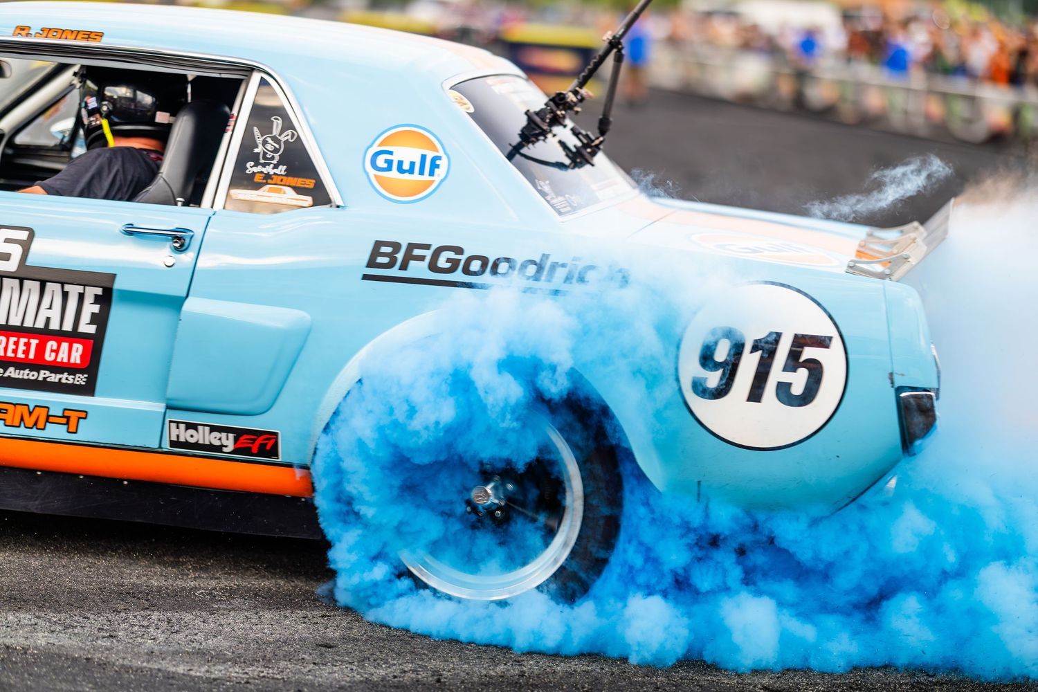 Gulf-sponsored car #915 with BFGoodrich tires performs a burnout, creating dramatic blue tire smoke on the racetrack.