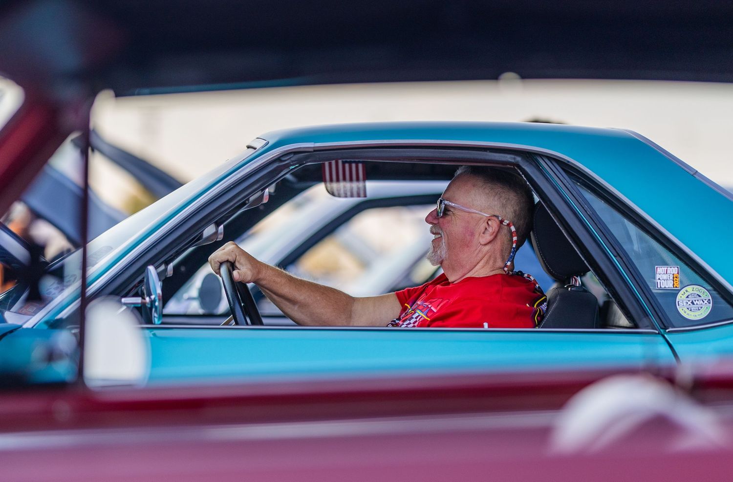 Classic car enthusiasts gather at an outdoor auto show displaying vintage vehicles.