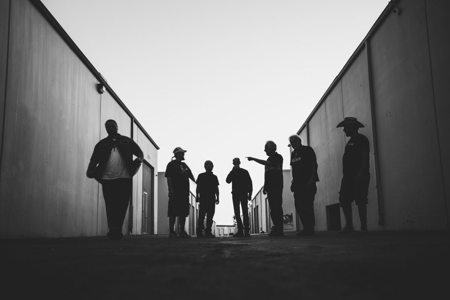 Silhouettes of people standing against bright background creating dramatic contrast.