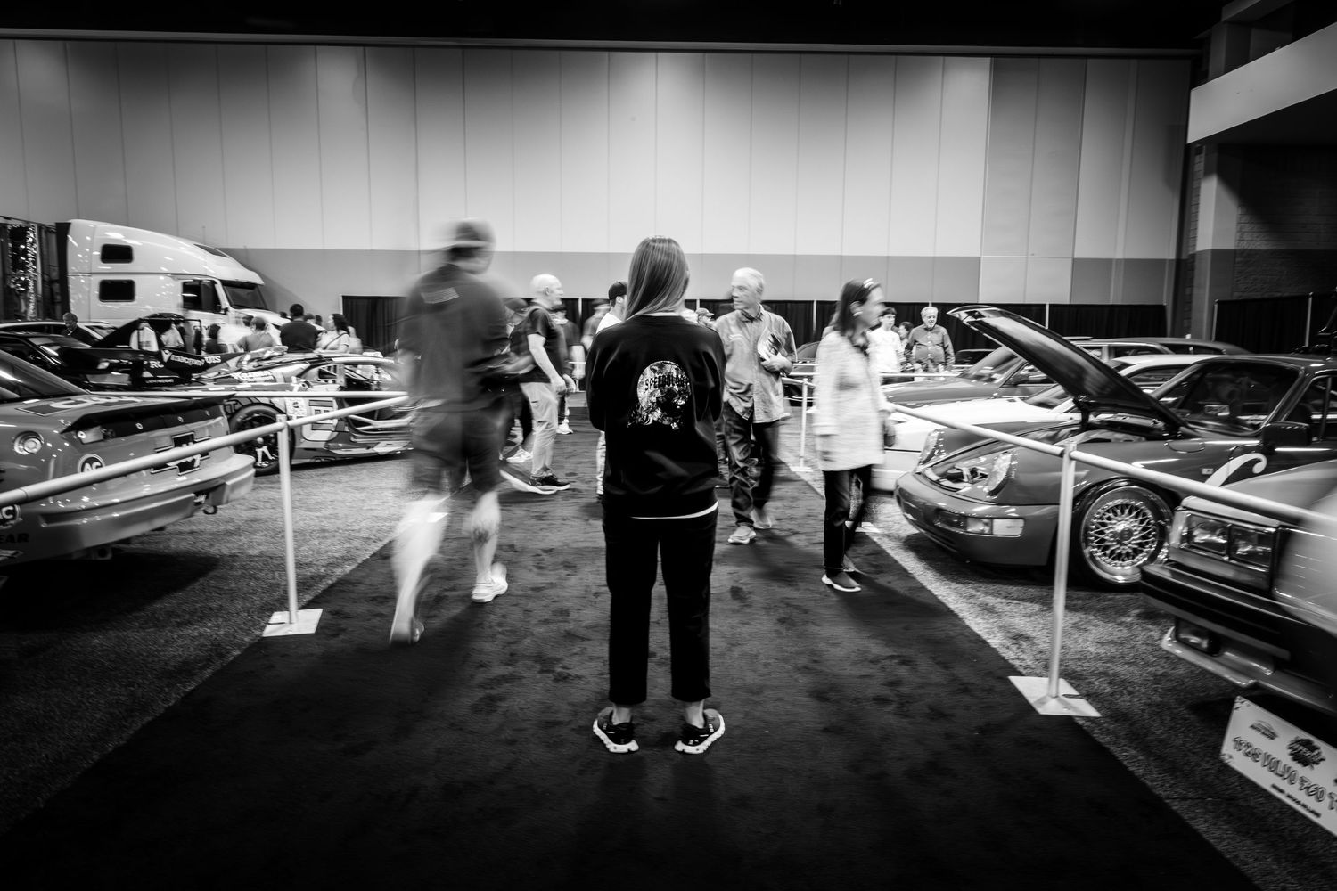 Black and white wide-angle view of people walking through an indoor venue.