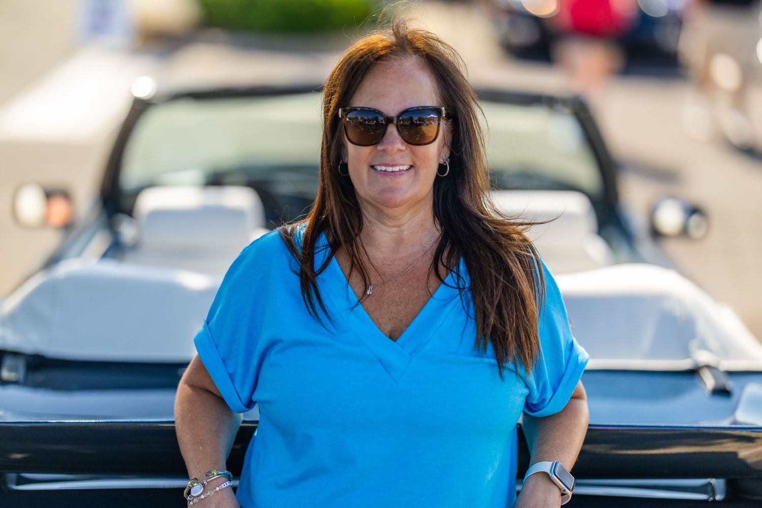 Woman in bright blue shirt at classic car show event.