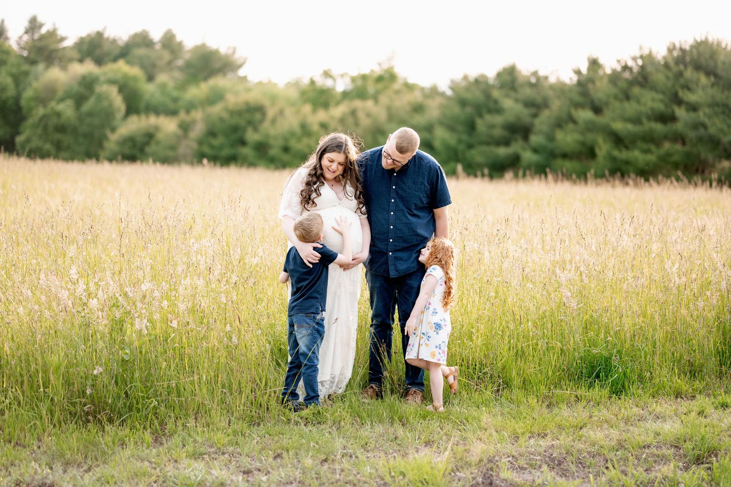 Family walking through a golden  field on a sunny summer afternoon in matching white and blue outfits.