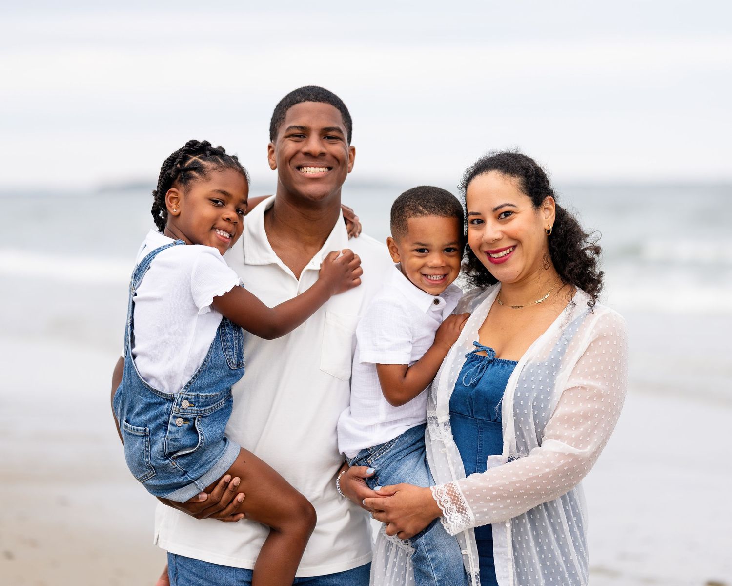 Family enjoying a day together at the beach wearing coordinated white and blue outfits.
