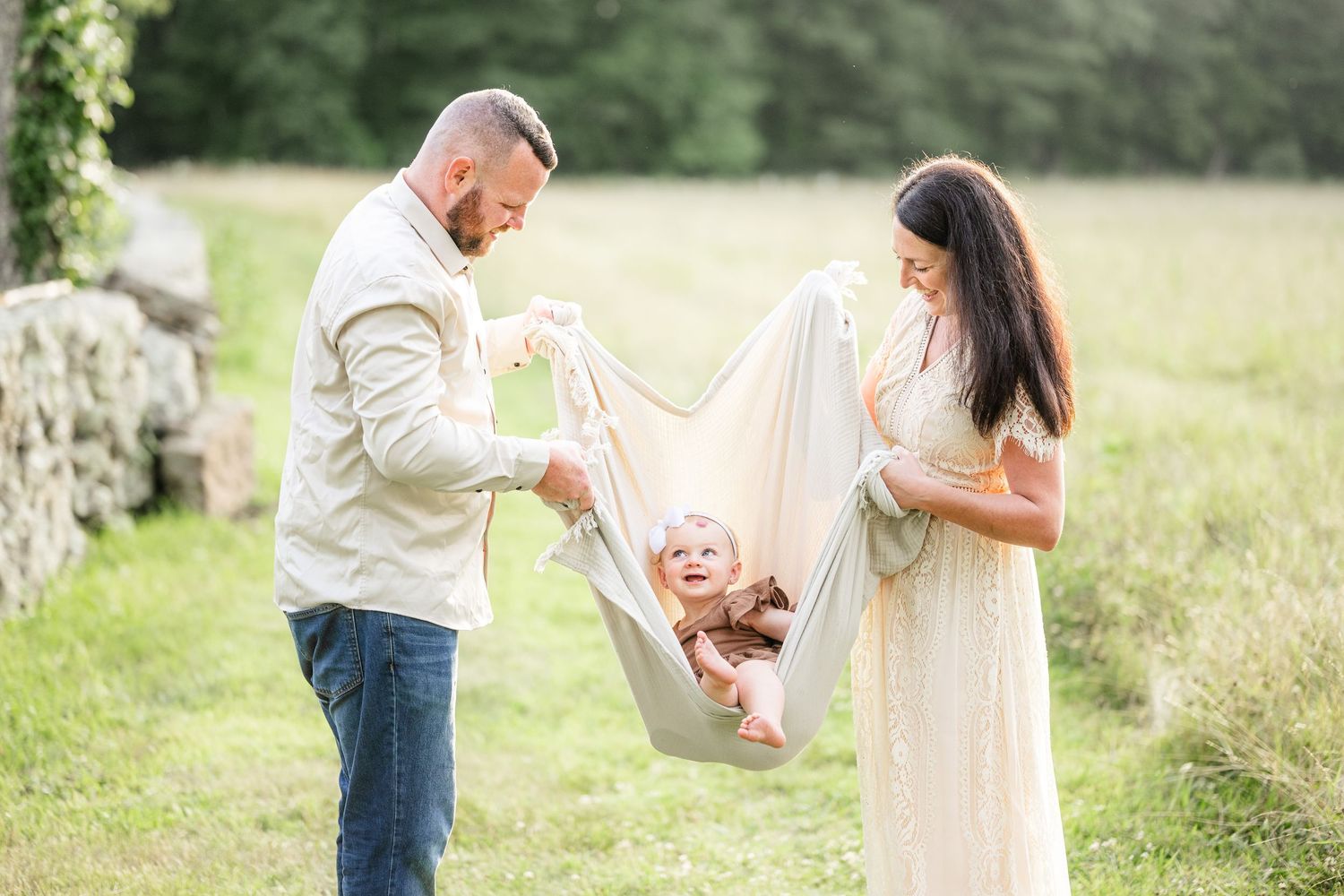 Family enjoys playful outdoor photo session in a sunlit meadow with white summer attire.