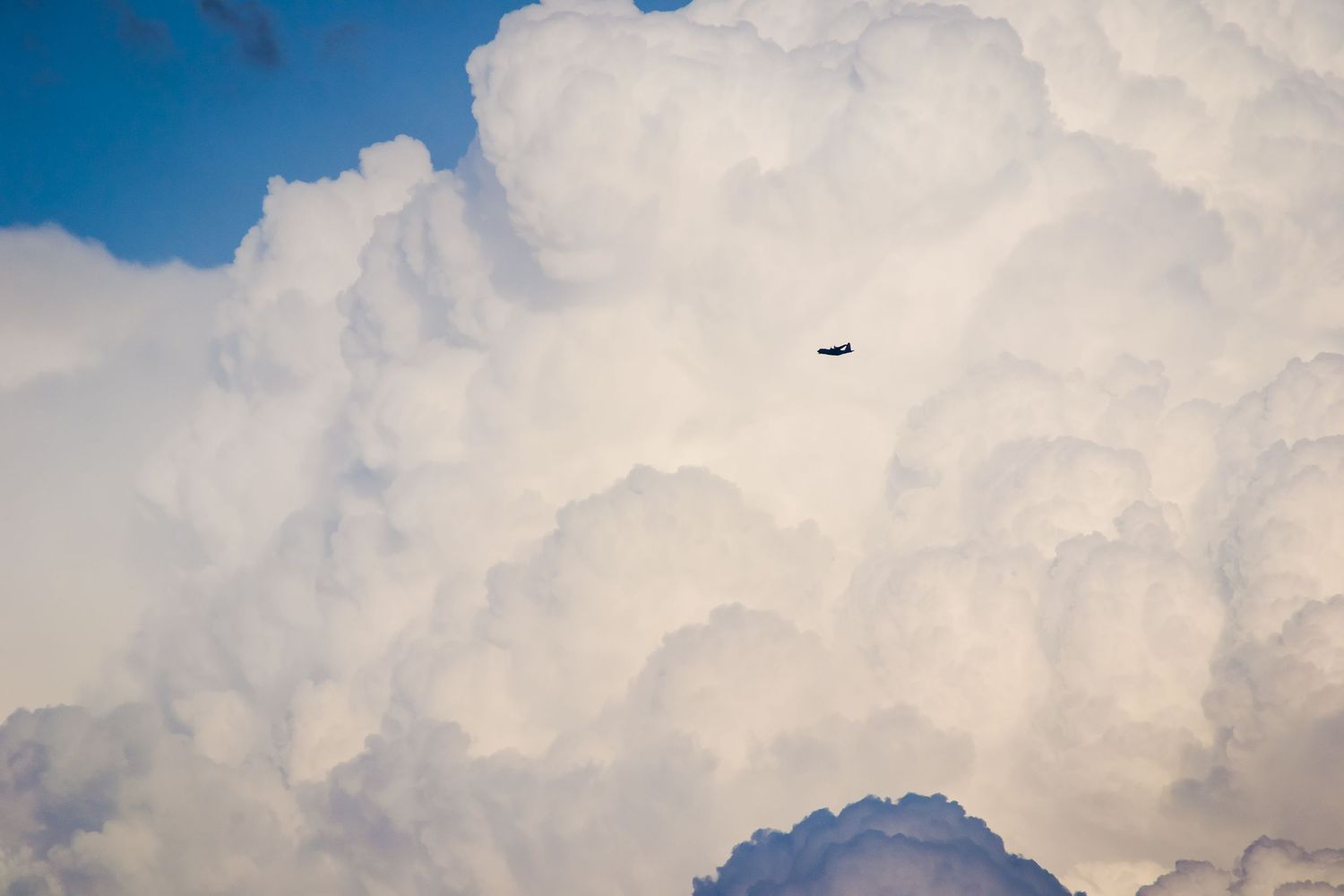 Photo of a cloud with a small plane in front.