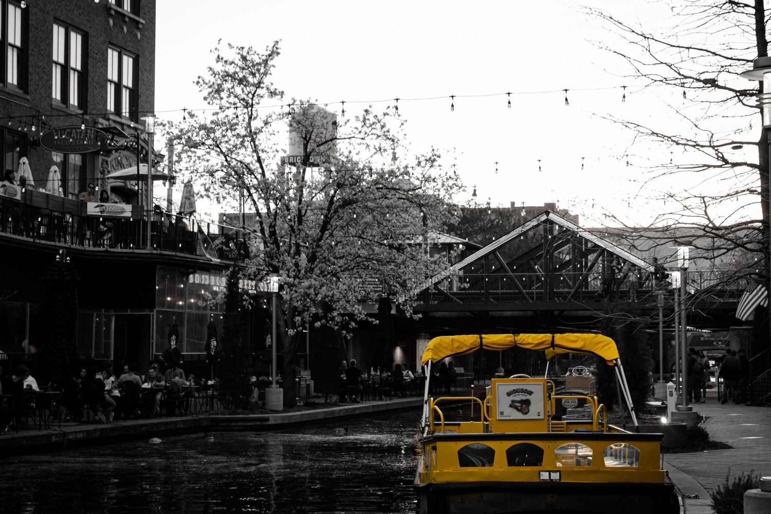 Black and white photo of Bricktown Canal in OKC with a yellow tour boat.