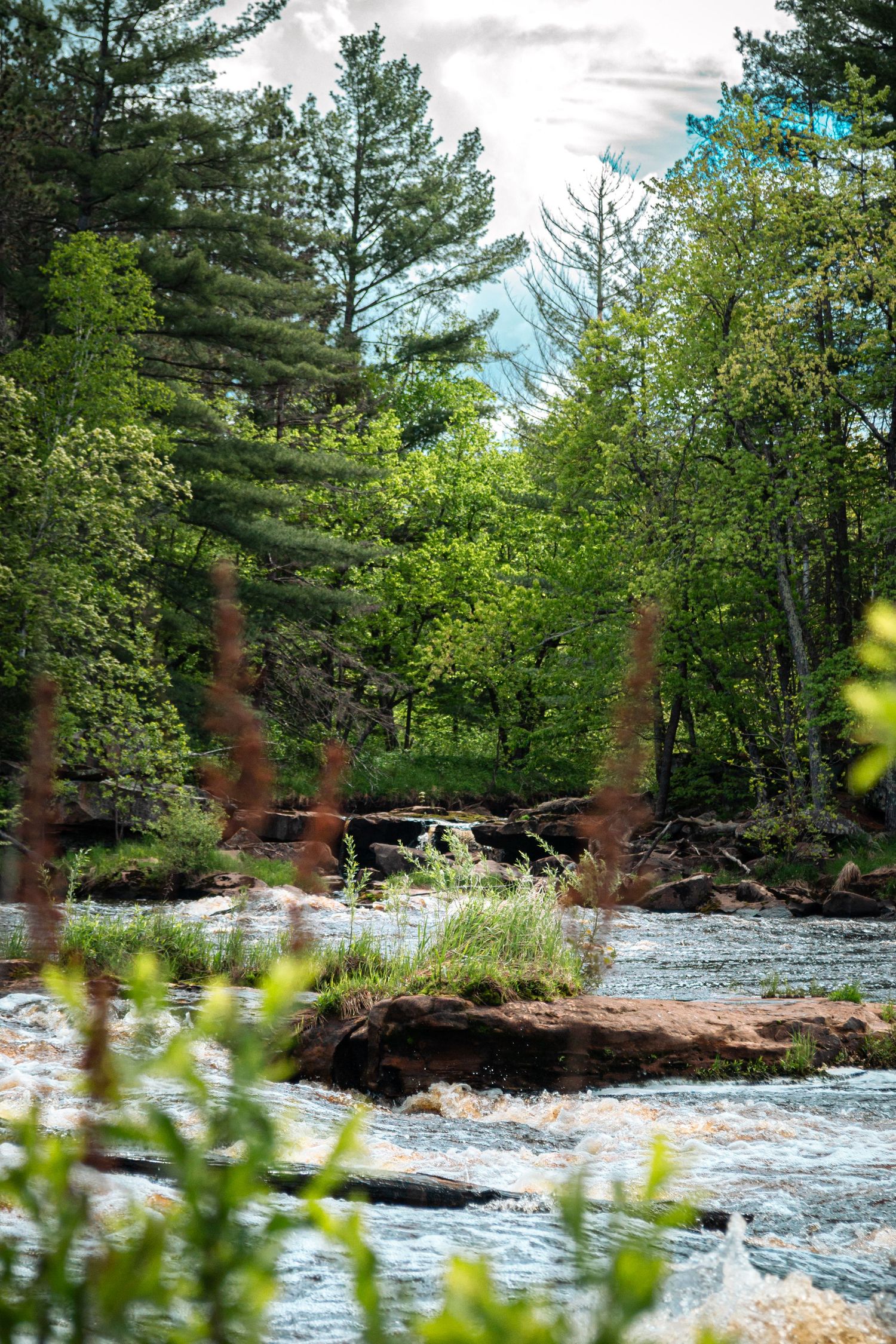 Photo of a river and an occluded waterfall in the back.