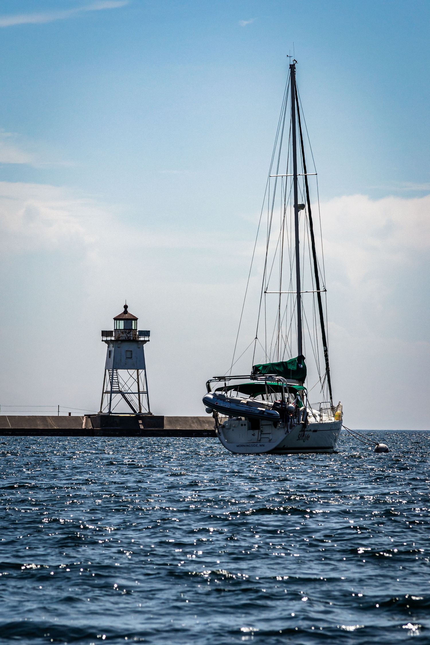 Photo of a sailboat and a lighthouse.