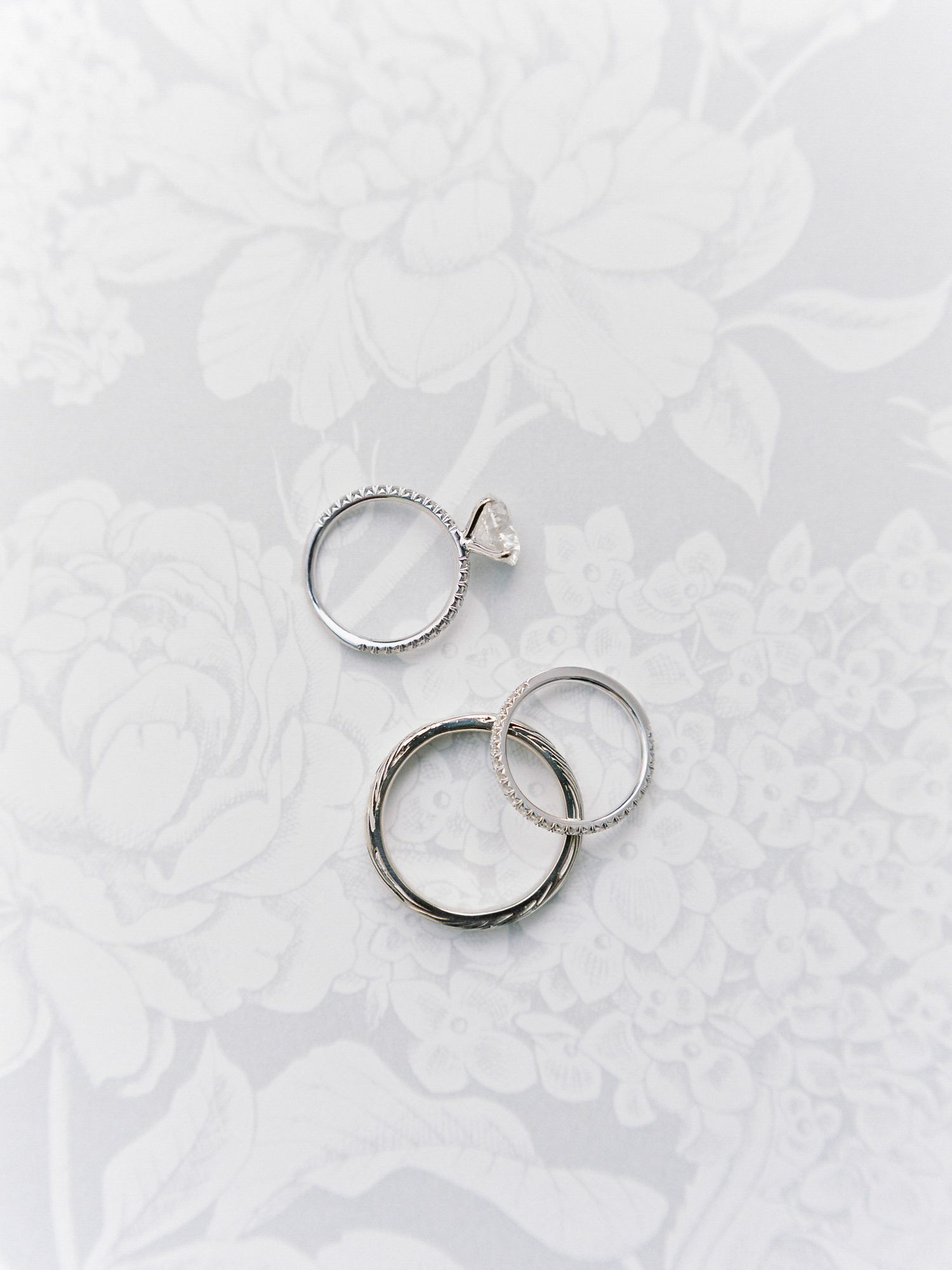 Wedding rings photographed on a light floral background with elegant composition in Napa.