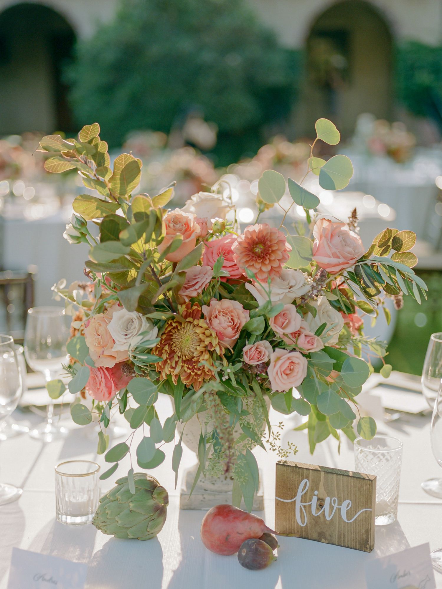 Wedding table centerpiece with coral and pink flowers, eucalyptus, and wooden table number at Sonoma Golf Club.