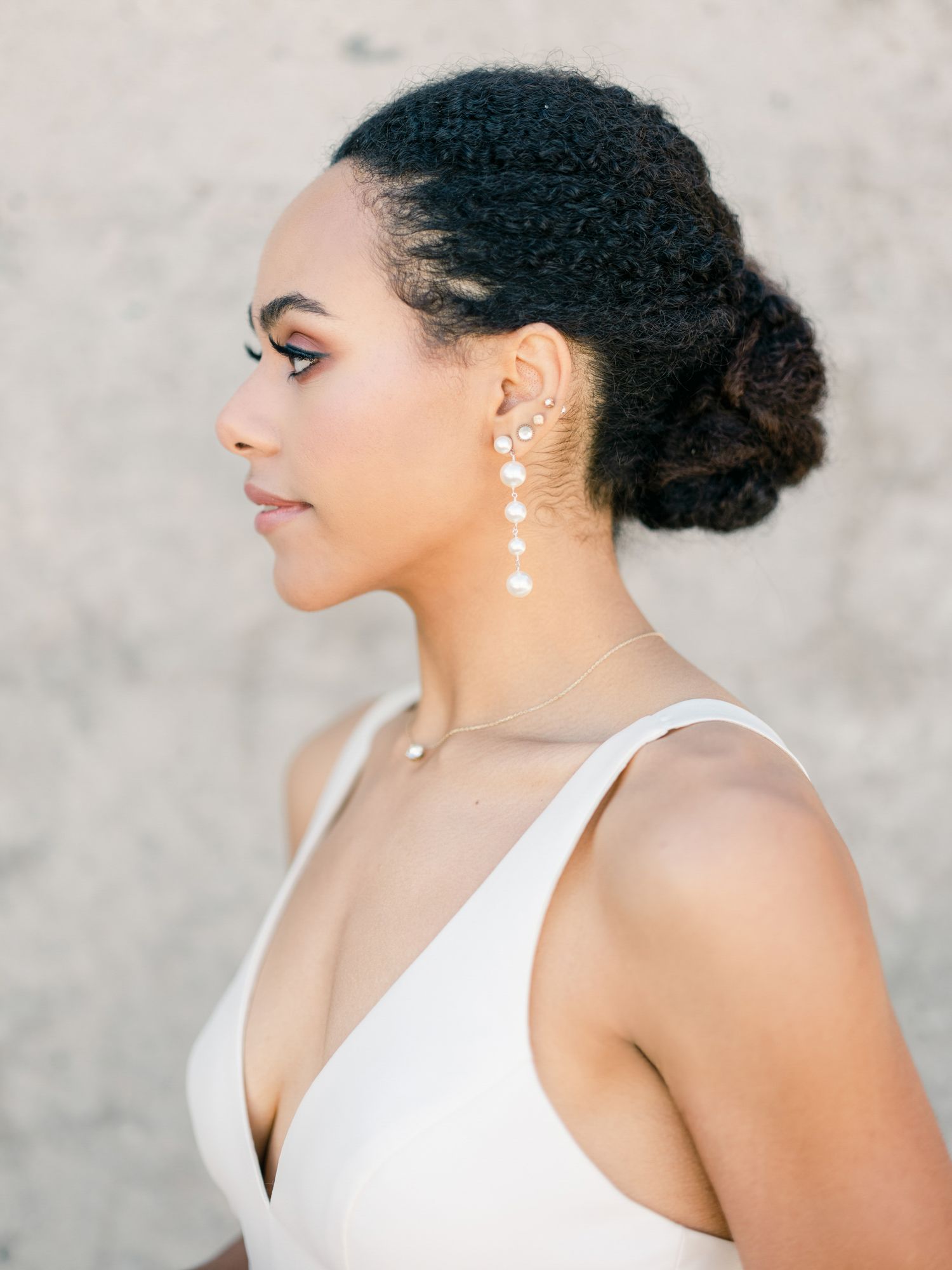Side profile of a bride wearing a white dress and pearl drop earrings with an elegant updo in Napa.