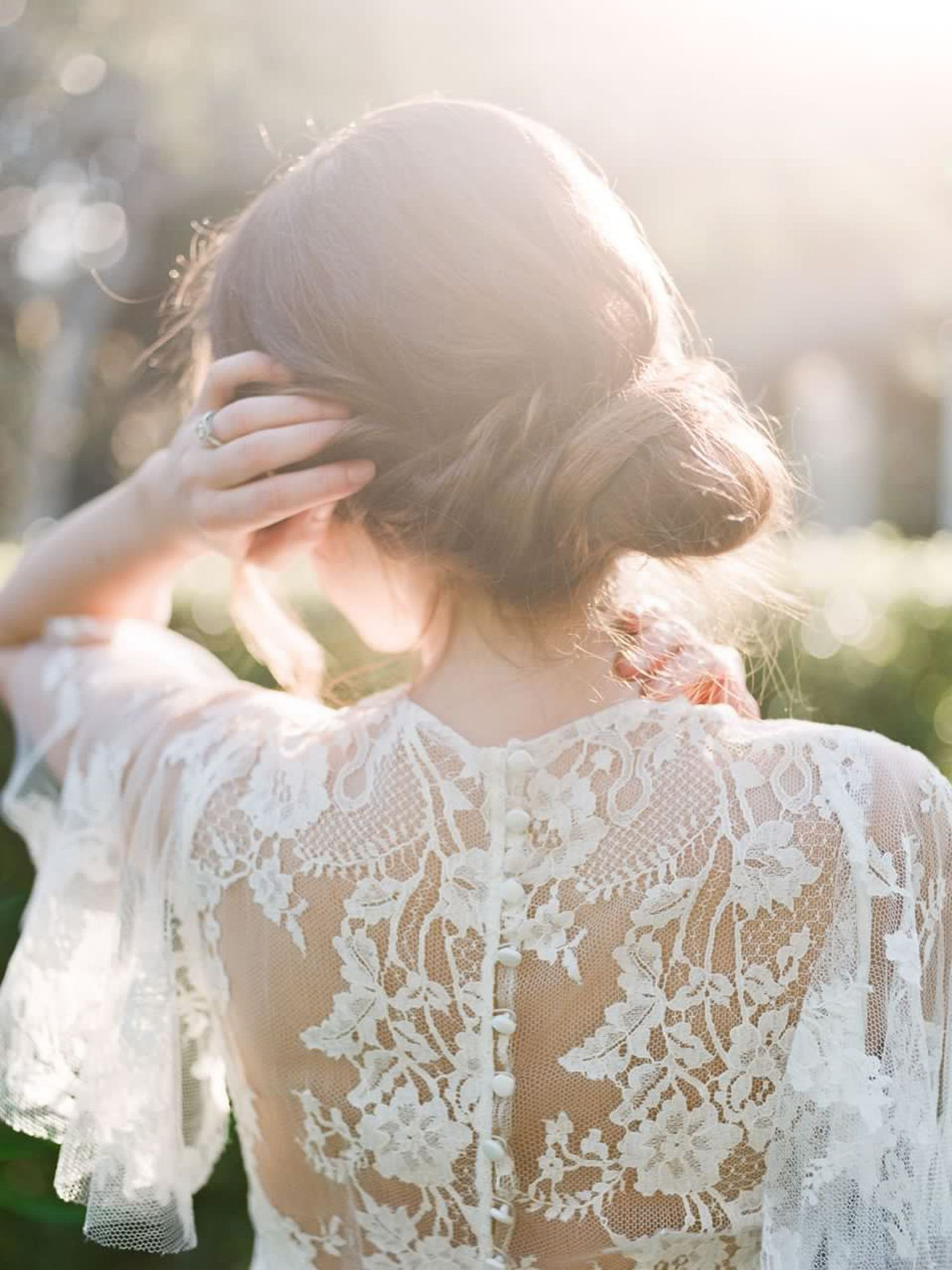 Delicate white lace detail on wedding dress sleeve backlit by soft sunlight at Allied Arts Guild in Menlo Park.