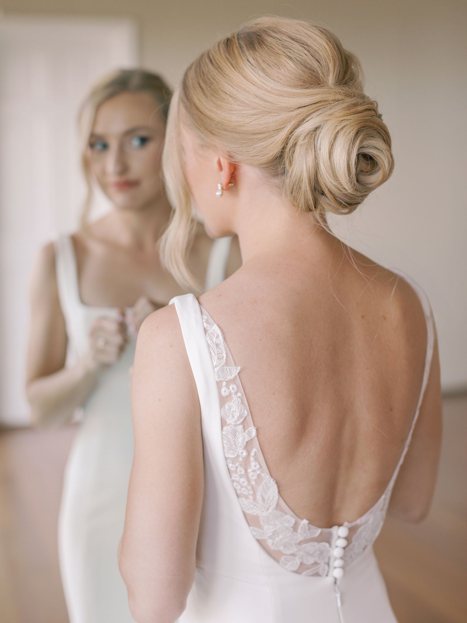 Elegant bridal updo and lace-back wedding dress reflected in mirror at Thomas Fogarty Winery in Woodside.