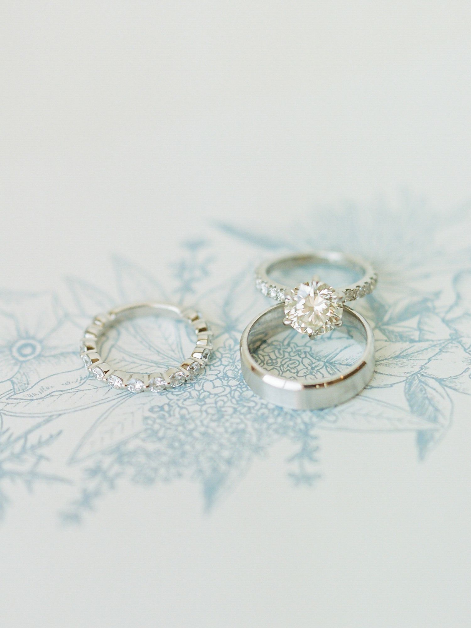 Diamond engagement ring and wedding band set photographed on light blue floral pattern at B.R. Cohn Winery in Sonoma.