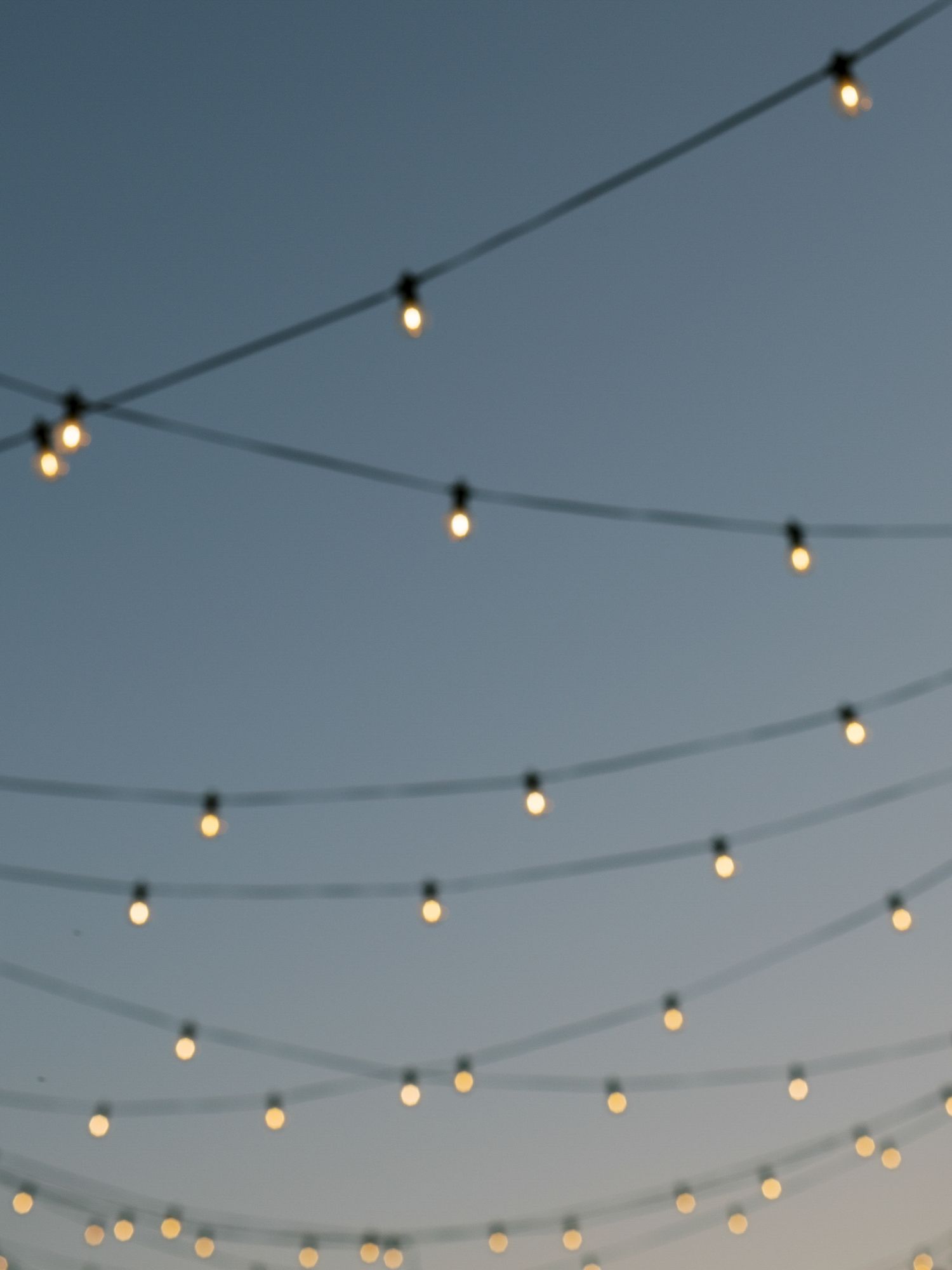 String lights hang elegantly against a dusky blue sky creating a romantic outdoor ambiance at Stanly Ranch in Napa.