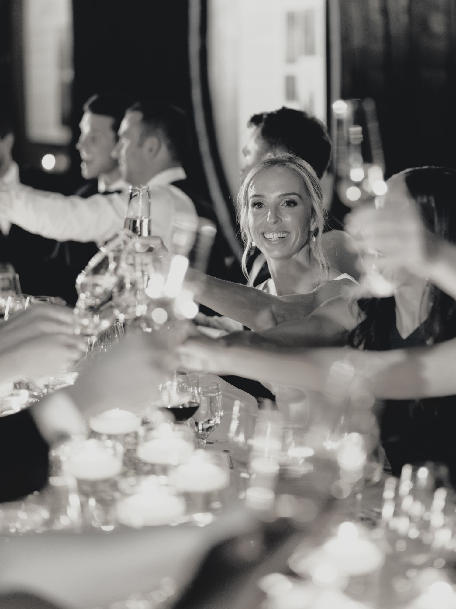 Candlelit wedding reception table with guests raising glasses in celebration at Greystone in St. Helena.