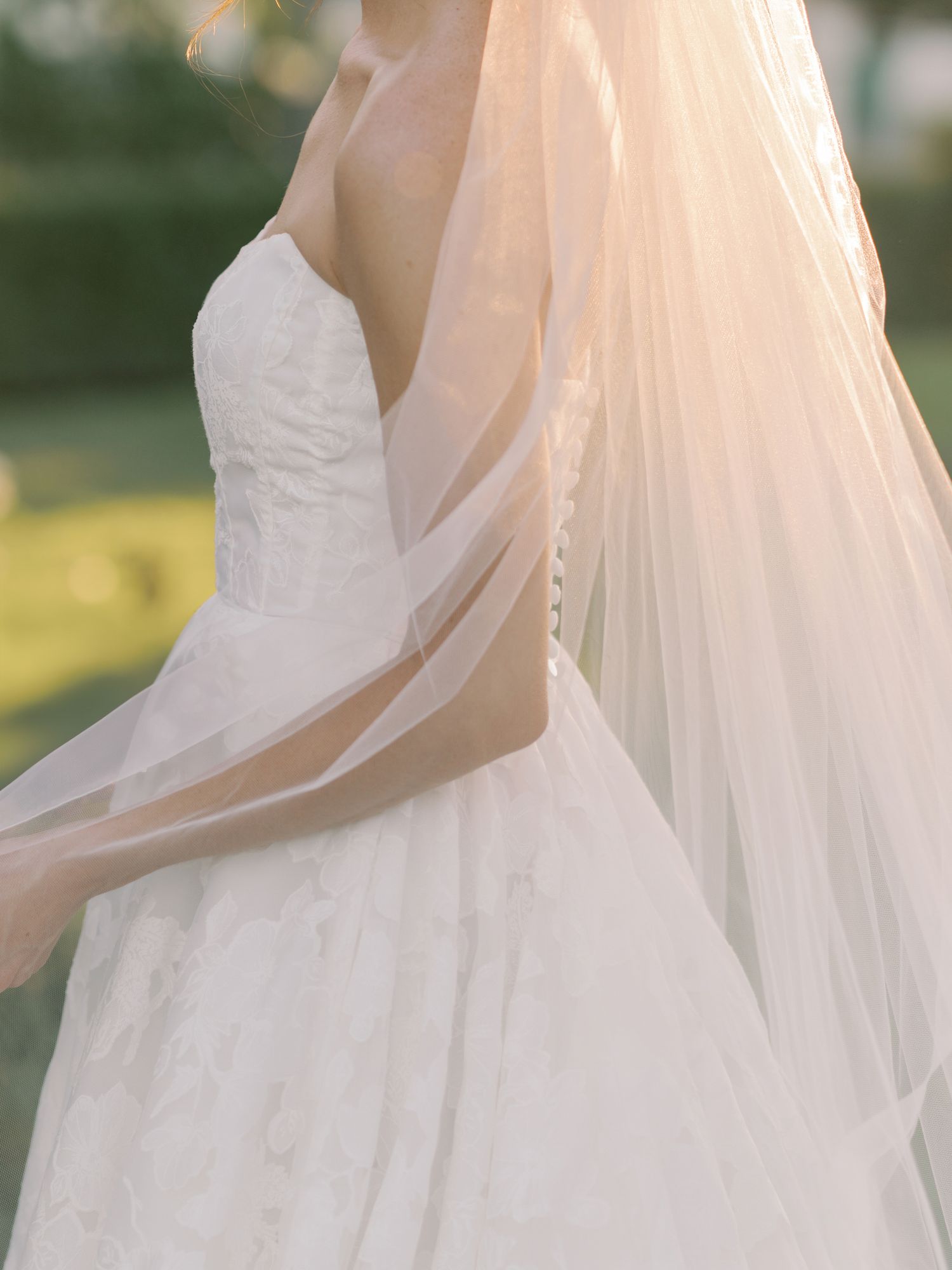 Close-up of a white wedding gown bodice with delicate veil flowing in sunlight at The General's Daughter in Sonoma.