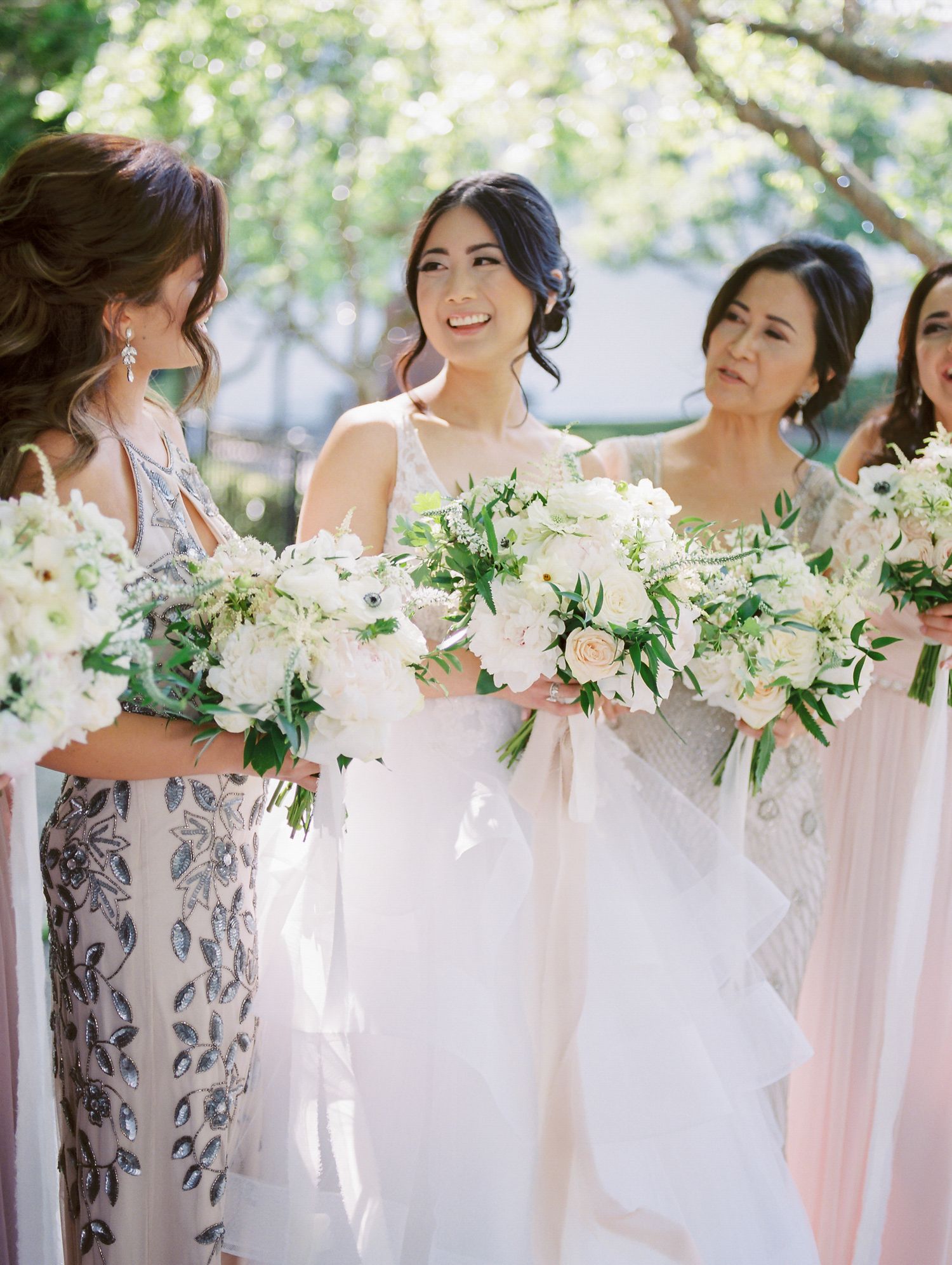 Wedding party with bridesmaids holding lush white and green bouquets in garden setting in Napa.