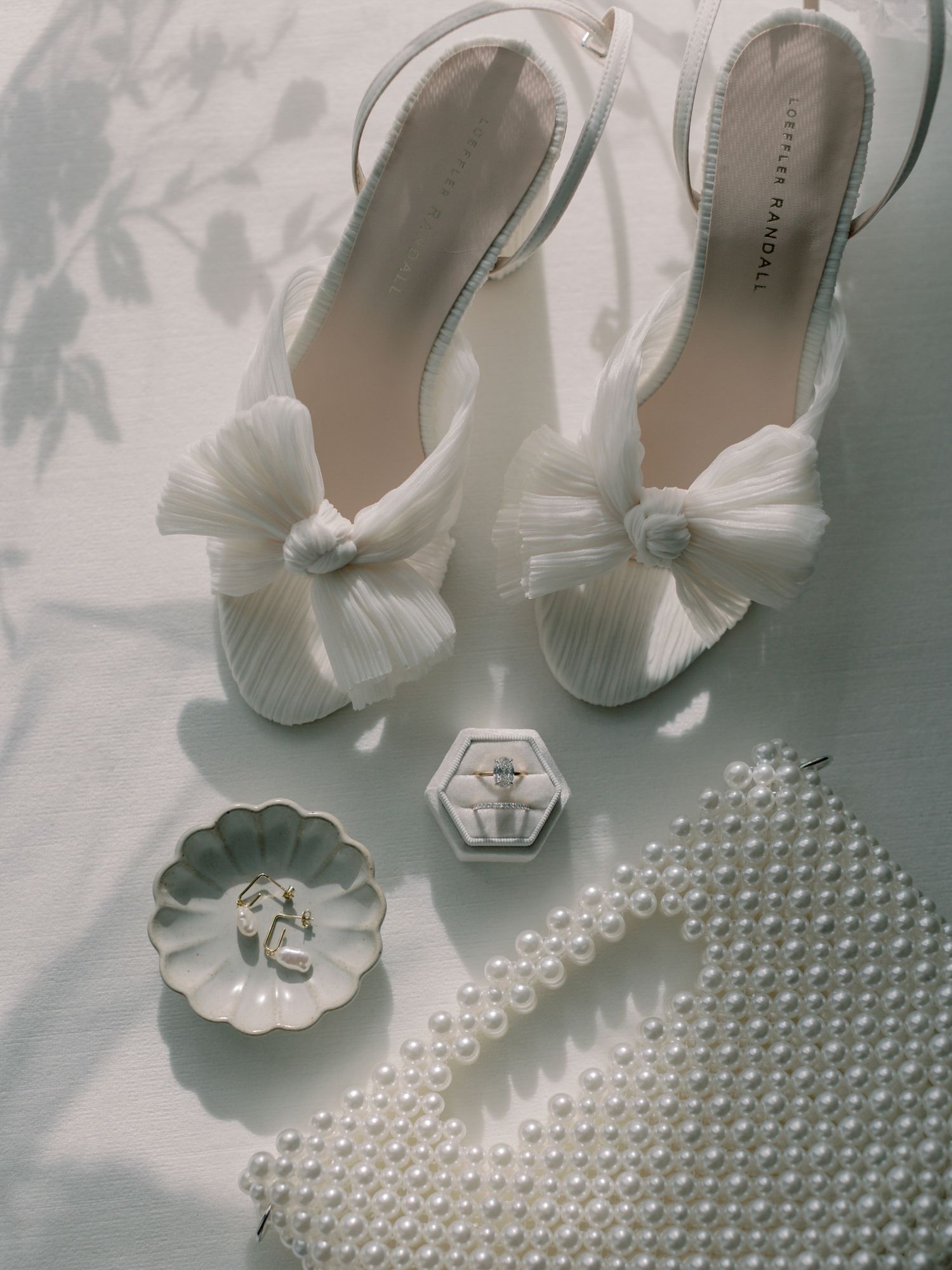 White bridal shoes with bow details displayed with pearls and ring holders at Greystone in St. Helena.