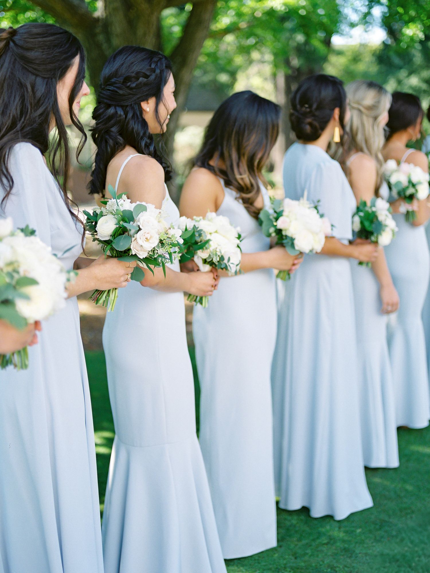 Row of bridesmaids in pale blue dresses hold white bouquets during outdoor ceremony at Claremont Country Club in Oakland.