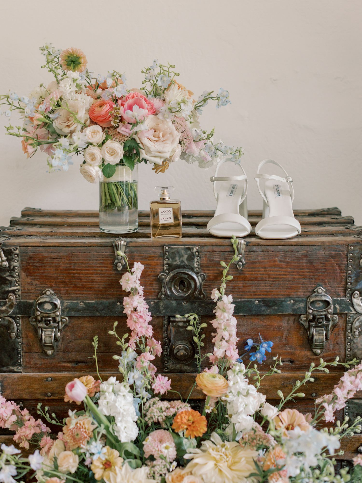 Vintage wooden chest decorated with floral arrangements and white bridal shoes in Napa.