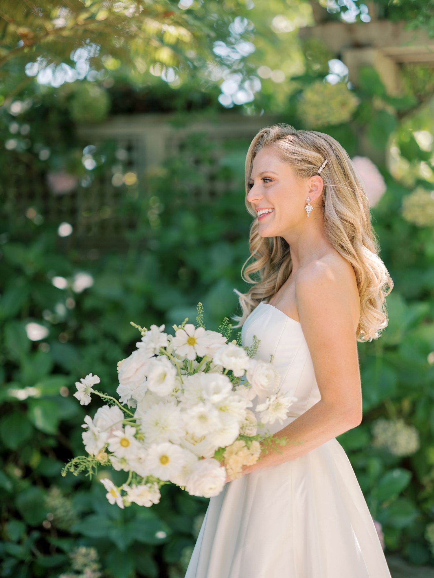 A white floral bouquet complements an elegant wedding dress in a garden setting at Vine Hill House in Sebastopol.