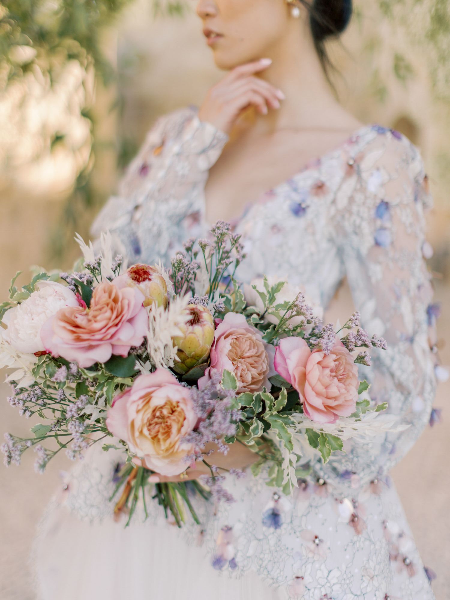 Close-up of a romantic bouquet with pink roses against a delicate lace wedding dress at Sunstone Winery in Santa Ynez.
