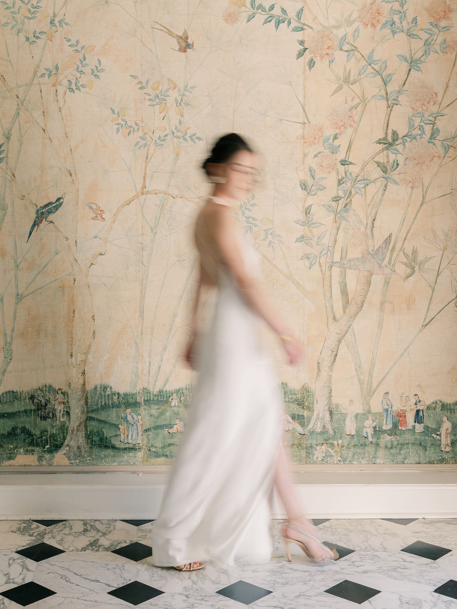Artistic motion blur of figure in white dress against chinoiserie wallpaper in Napa.