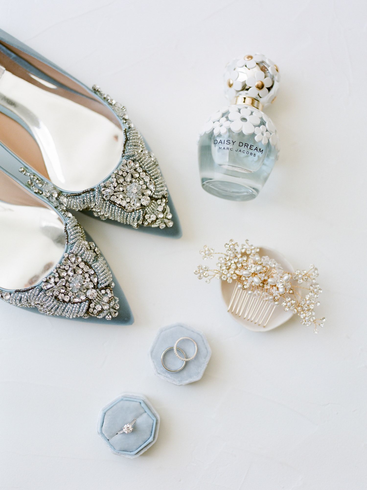 Wedding accessories including jeweled shoes, perfume, hair comb and rings on white background in Napa.