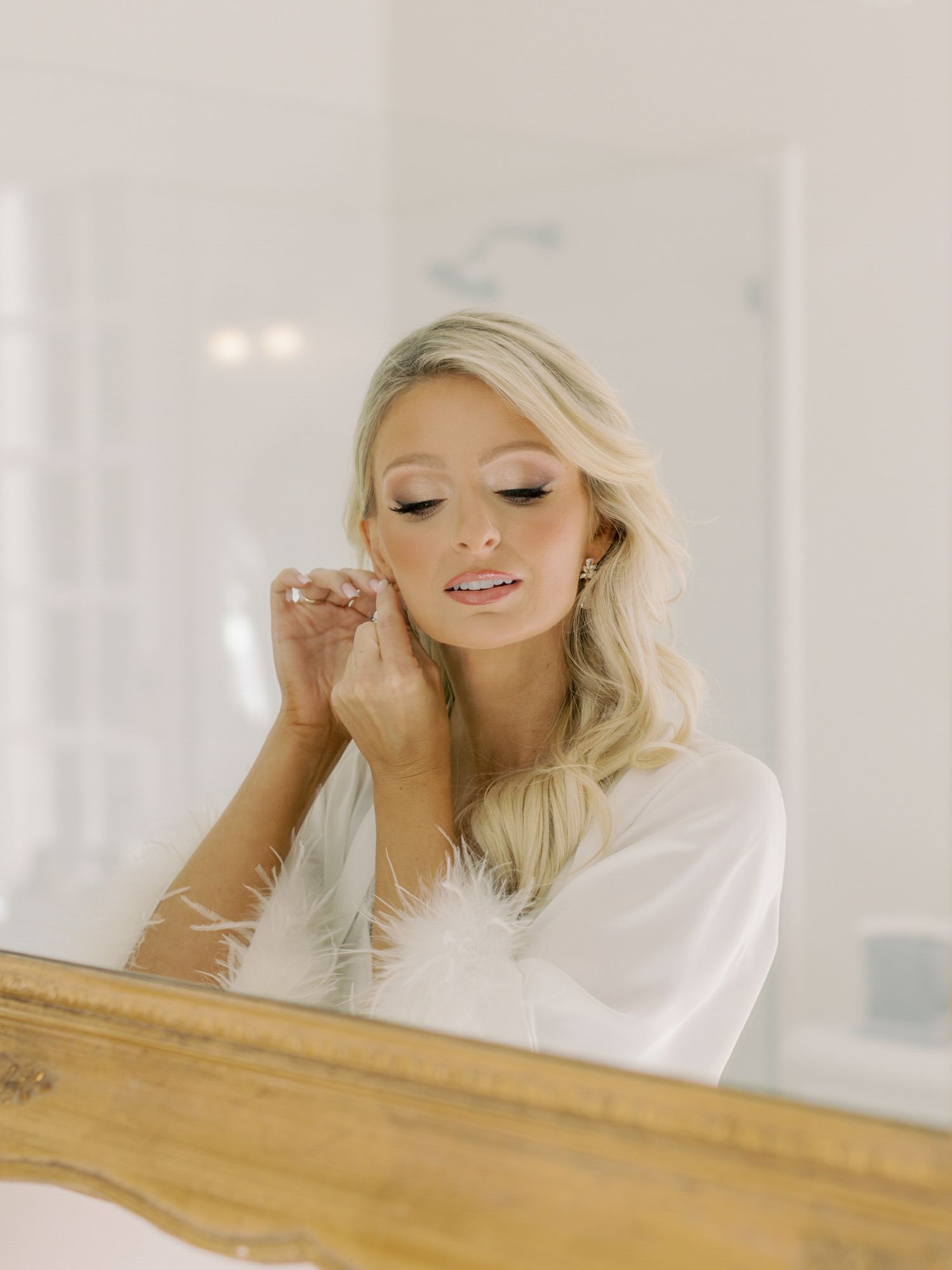 A bride getting ready at Park Winters in white robe while putting on earrings.