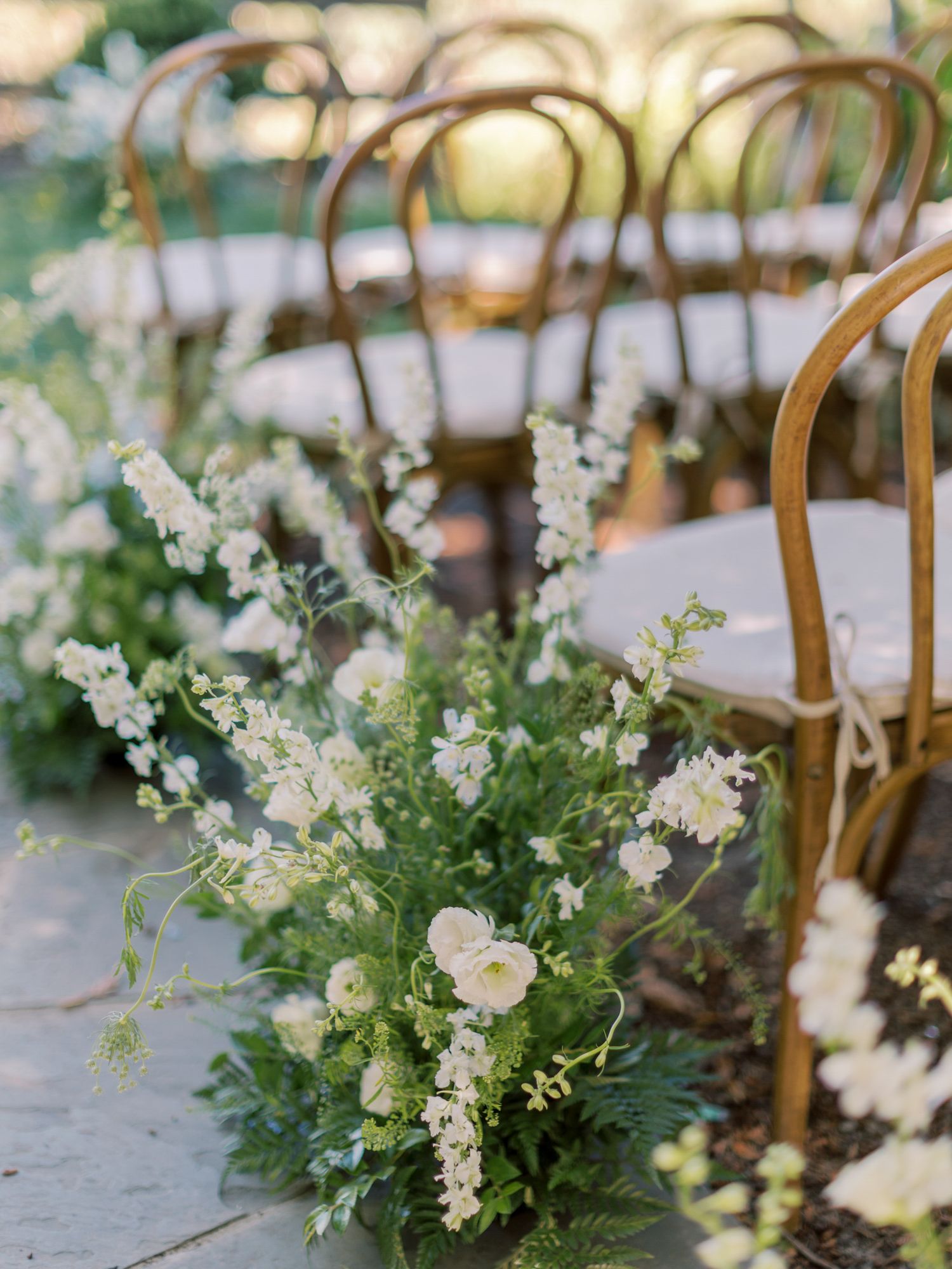 Rustic wedding ceremony setup with wooden chairs and white floral arrangements at Vine Hill House in Sebastopol.