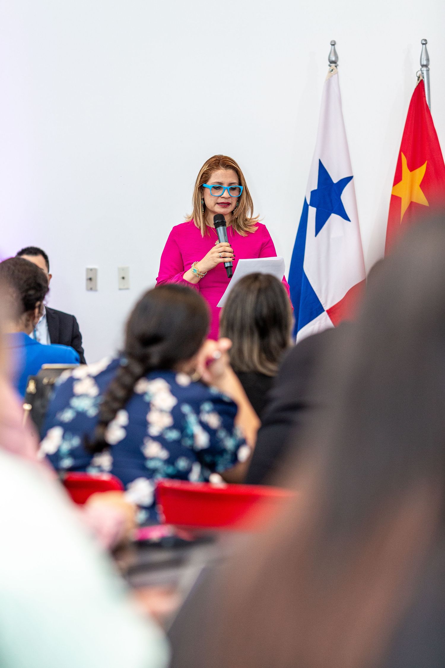 A crowd of people gathered at an event with national flags including American and Chinese flags in the background.