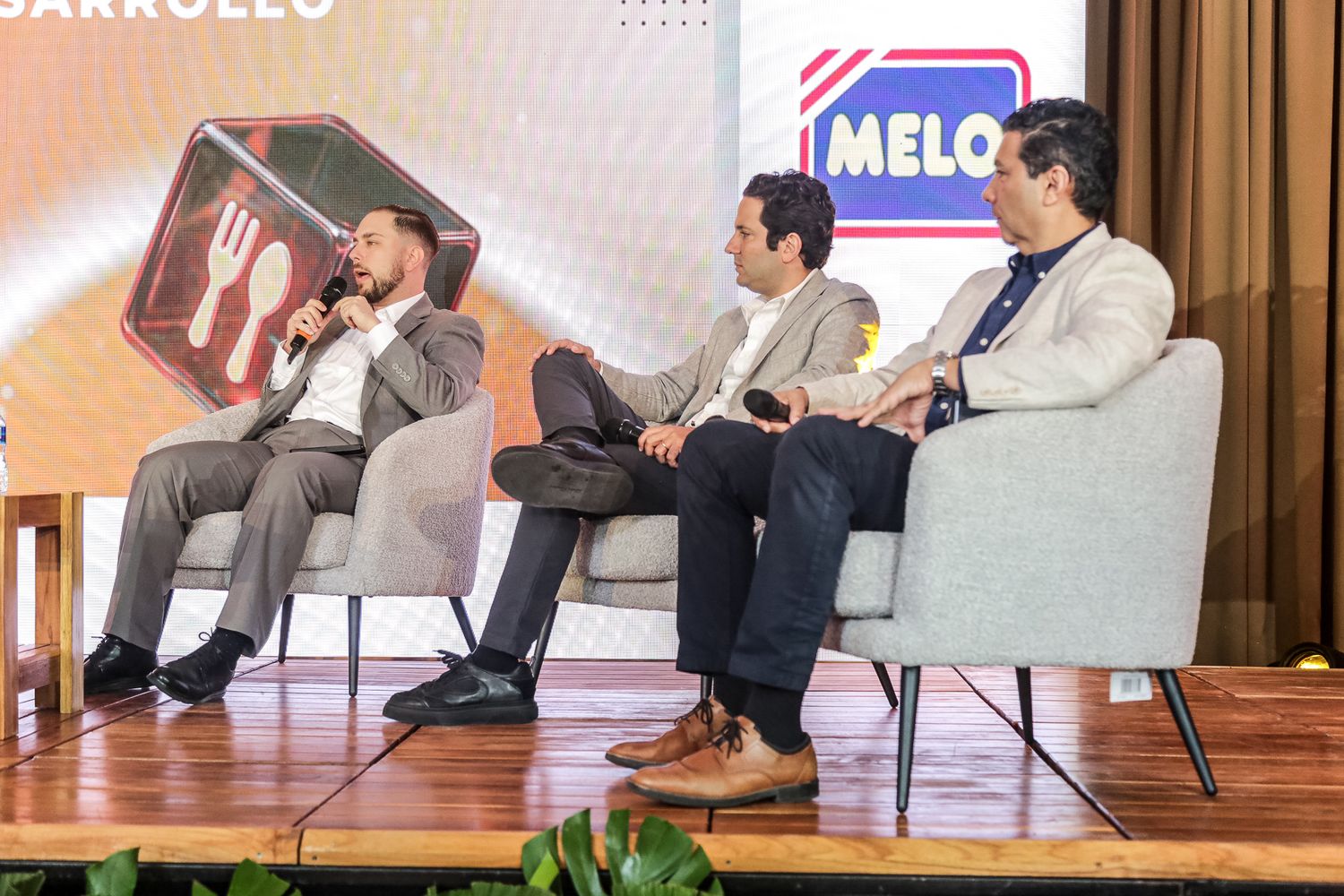 Panel discussion participants sit in white chairs on stage during a business conference event.