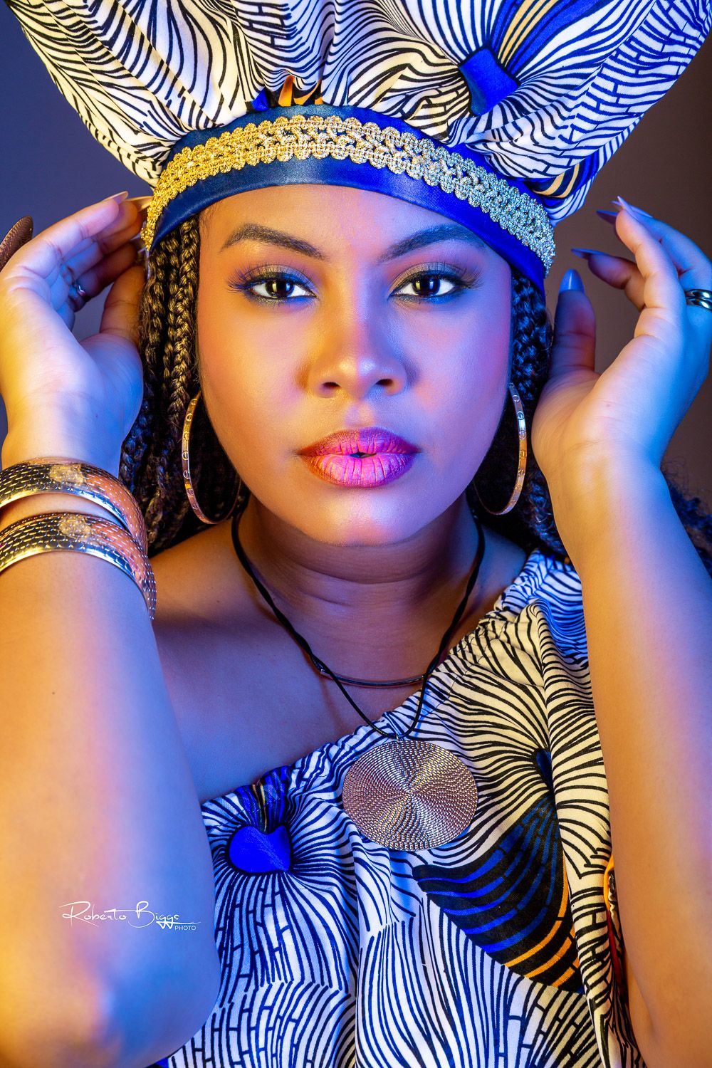 Fashion portrait with blue and white patterned fabric, gold headpiece, and dramatic lighting creating a regal mood.