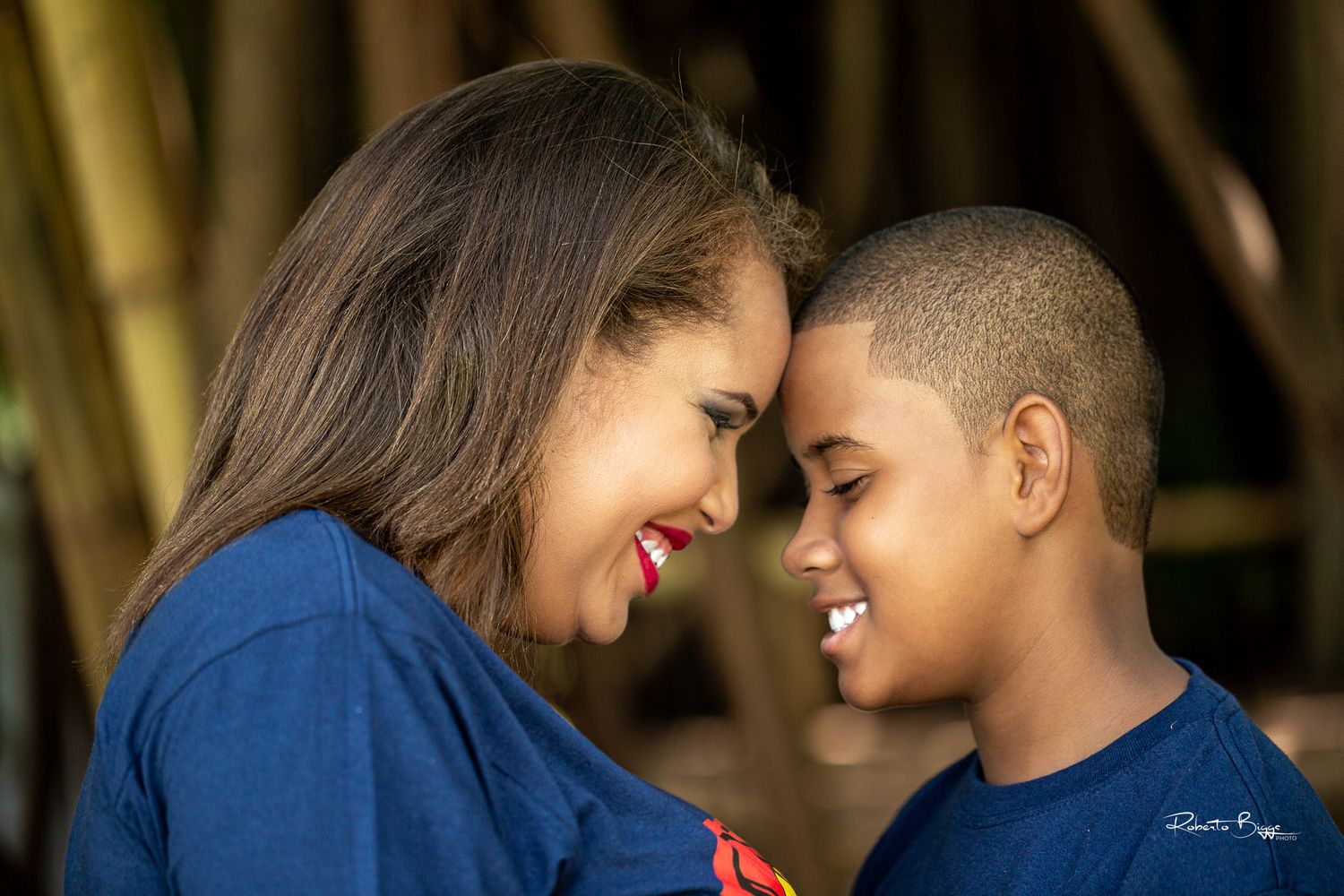 A tender moment shared between parent and child as they lean in close together while wearing blue clothing.