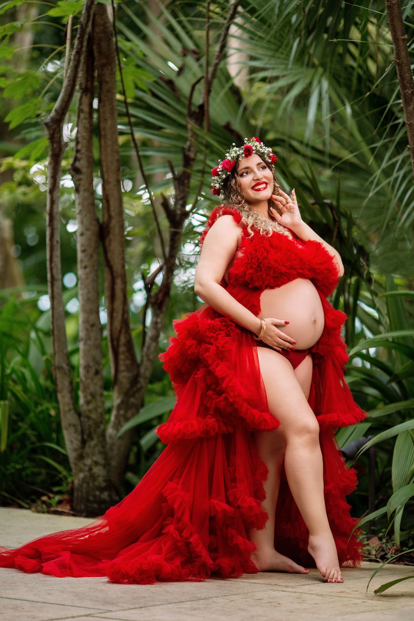 A series of photos in a tropical garden featuring someone in a dramatic red tulle gown against lush greenery.