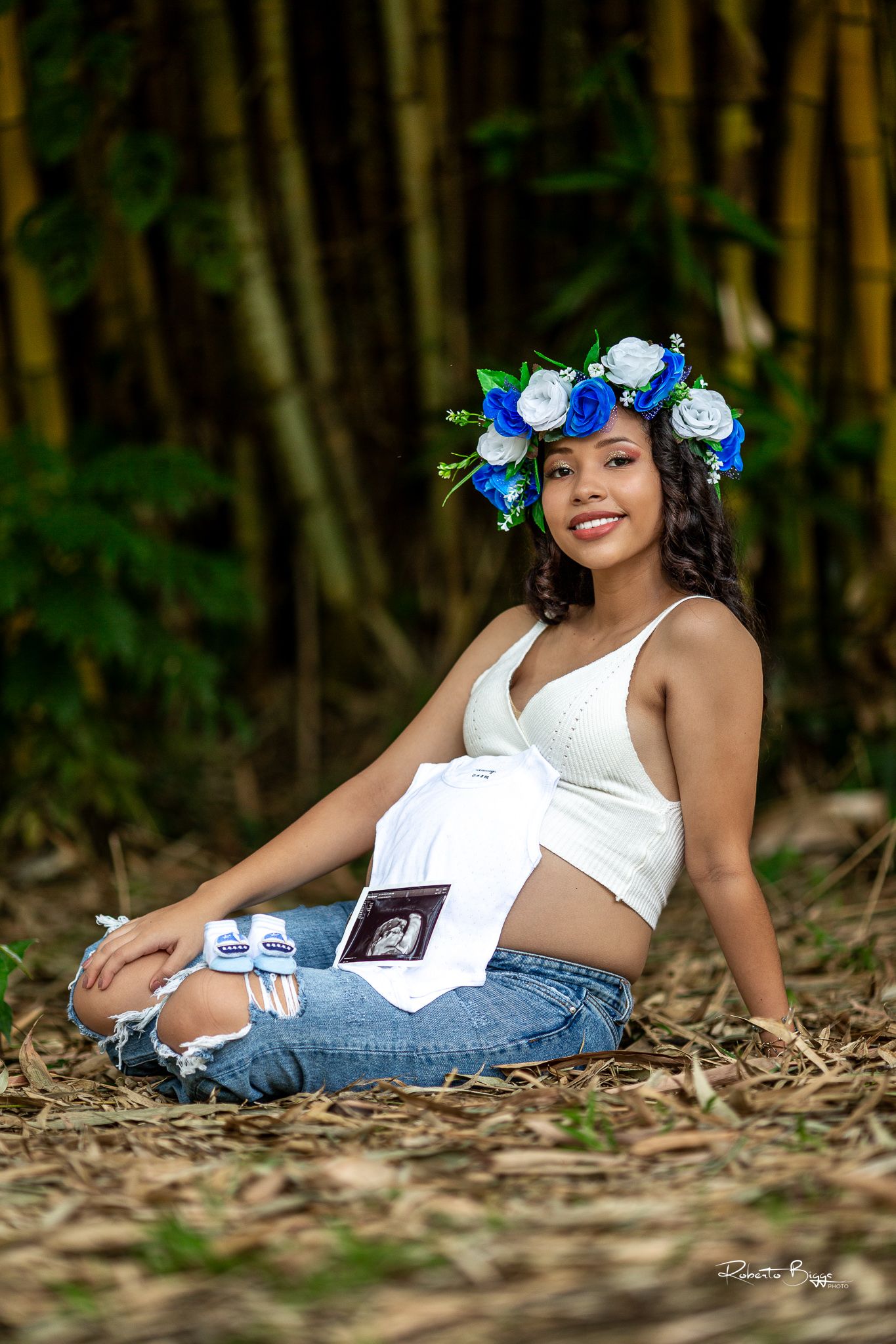 Maternity photo showing a flower crown and sonogram image in an outdoor bamboo forest setting.