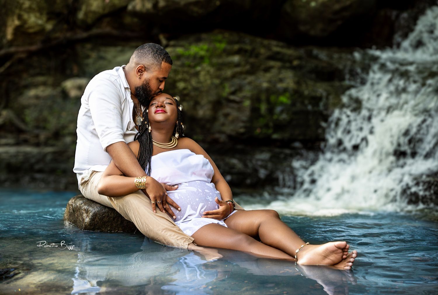 Romantic waterfall photoshoot featuring couple in white outfits.