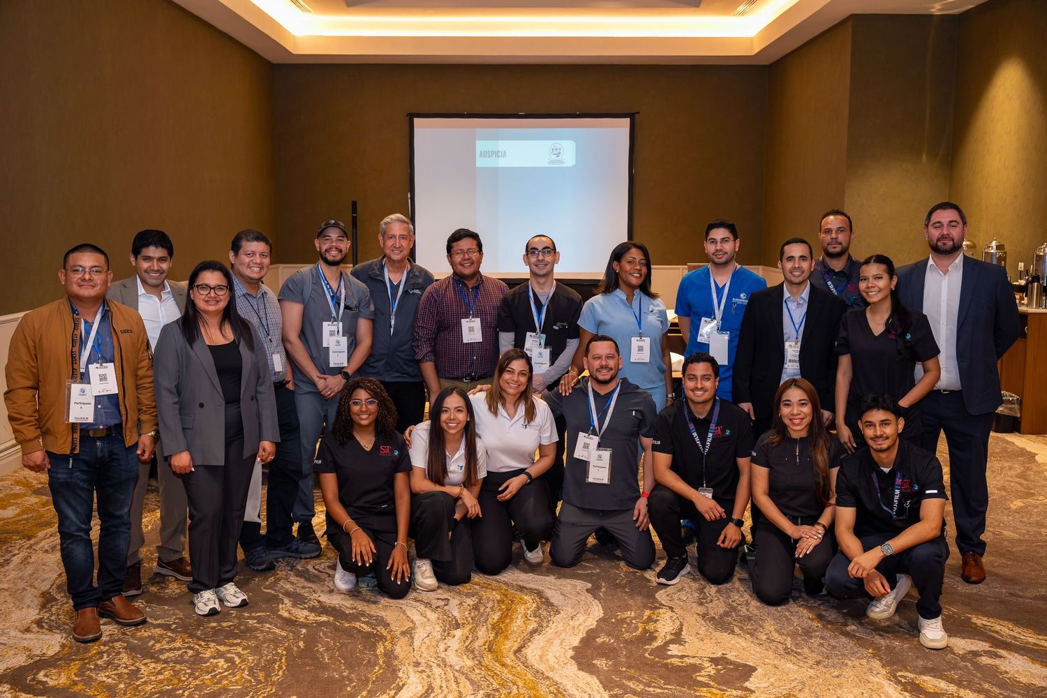 Large group of professionals posing together at a corporate conference event in a modern hotel ballroom.